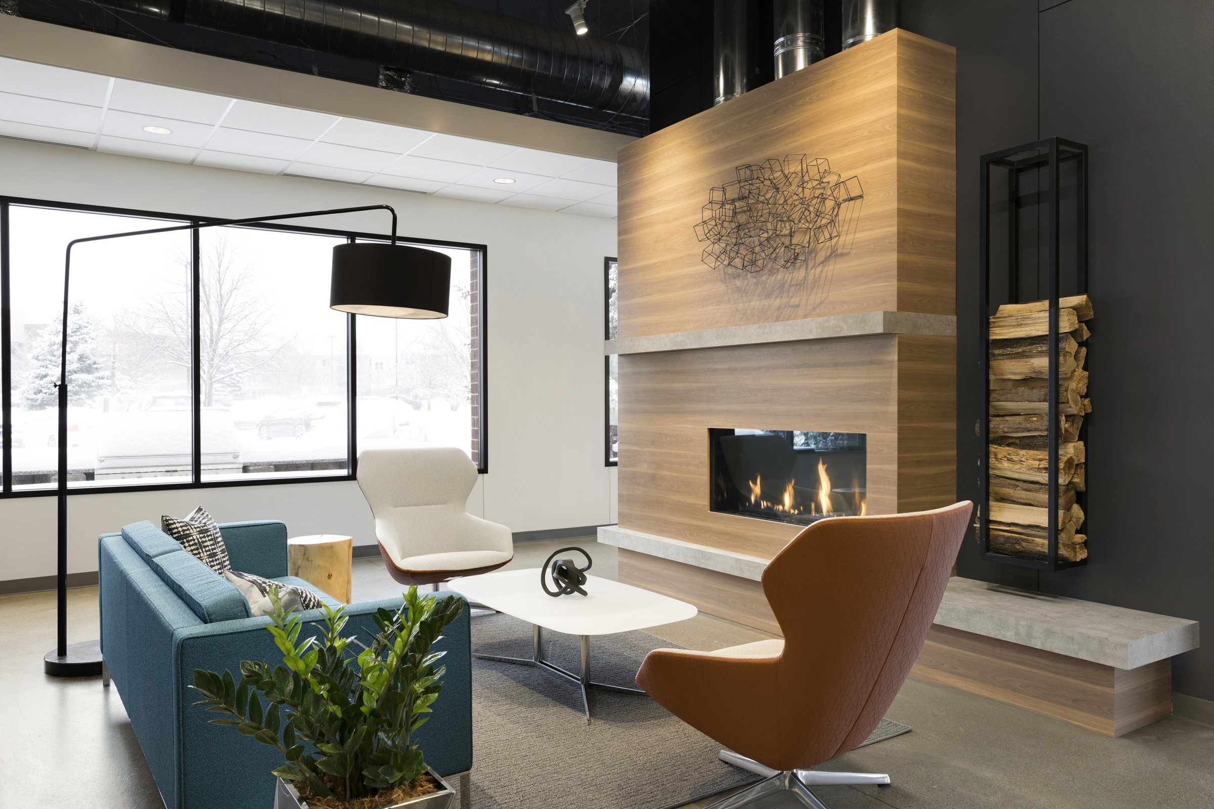 A crackling fire gives unexpected visual movement to this space and large open windows provide ample natural light and unobstructed views of nature. / Design by Vela Creative