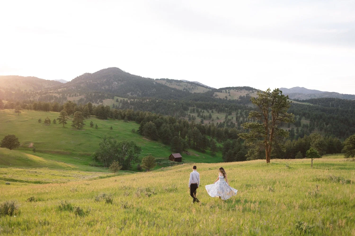 A couple twirls in a mountain meadow in Colorado during sunset, Golden engagement photographer.