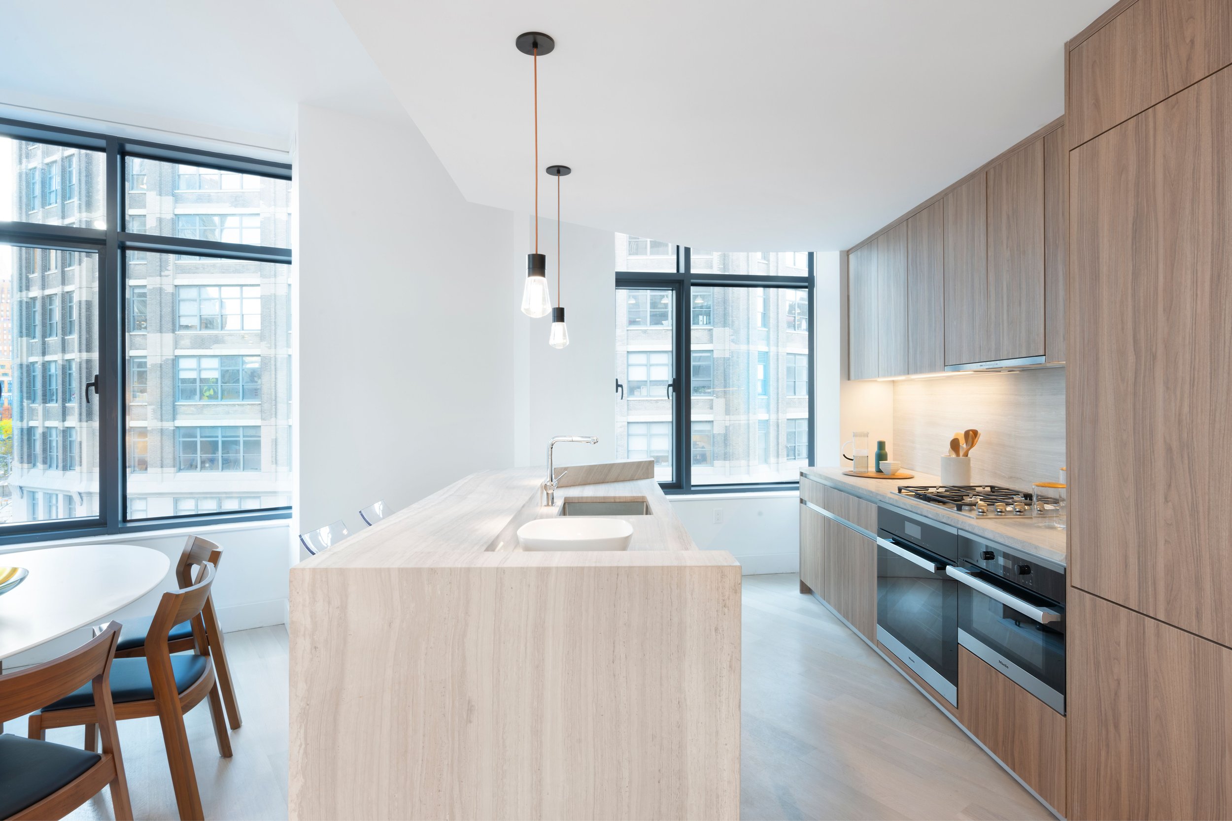  All residences have hardwood floors and ceiling heights up to 11 feet. Finishes in the kitchen include honed marble countertop and backsplash with custom kitchen cabinetry in Smoked Oak finish and built-in Miele appliances. In the primary bathroom, 