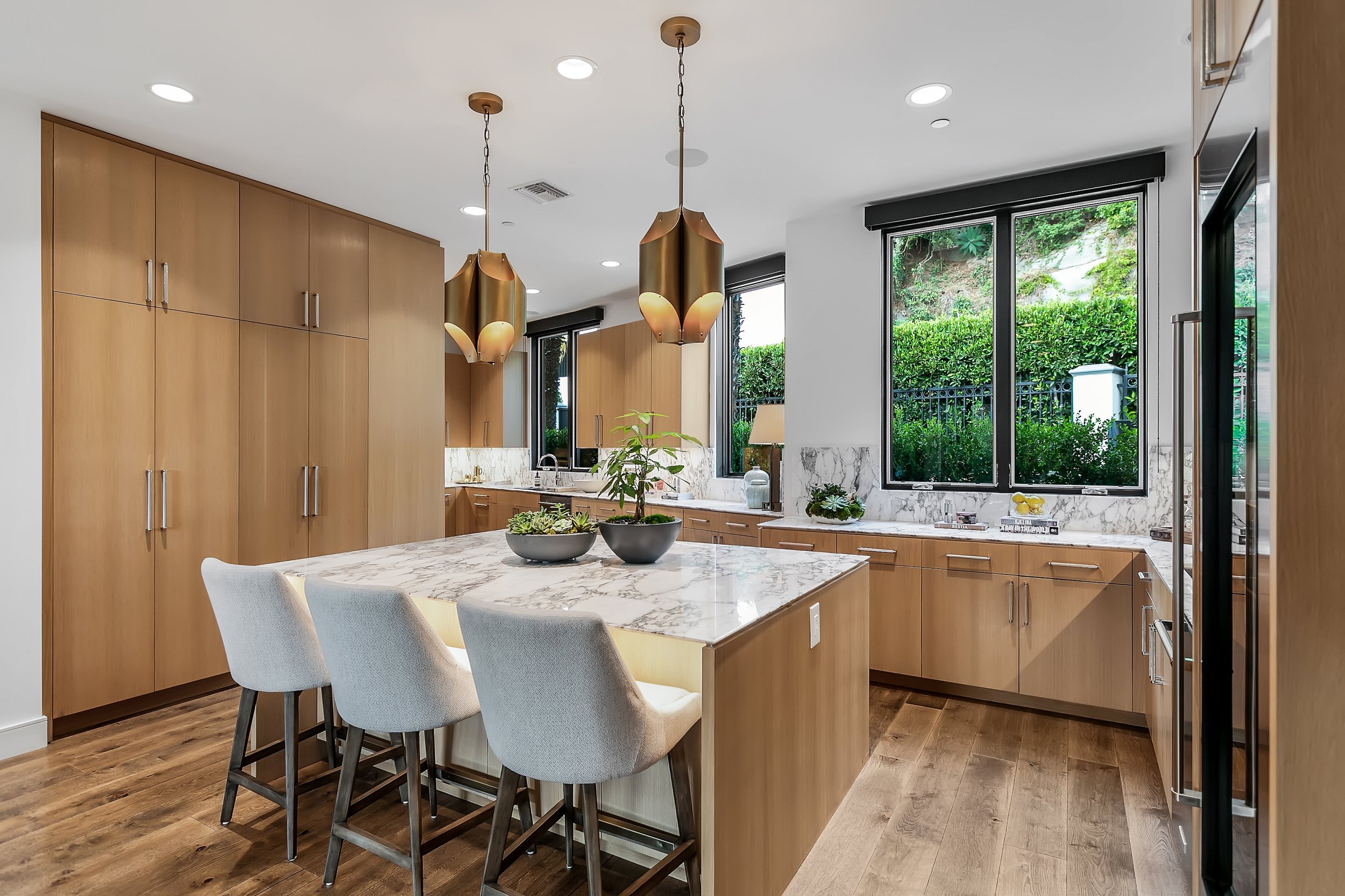  The oversized chef's kitchen exemplifies modern perfection with custom stained rift white oak cabinetry, dramatic polished Arabescato marble countertops and top-of-the-line Subzero/Wolf/KitchenAid/Miele appliances. 