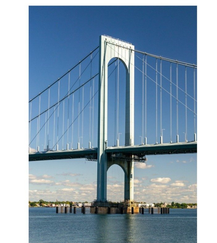 A tower of the Bronx-Whitestone Bridge rising over the East River on a clear day