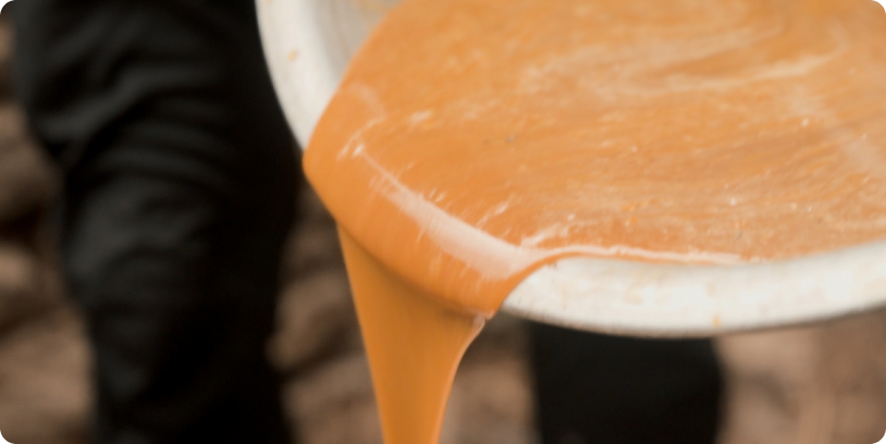 Honey flowing over the rim of a metal container in a Real Mad Honey sourcing photograph