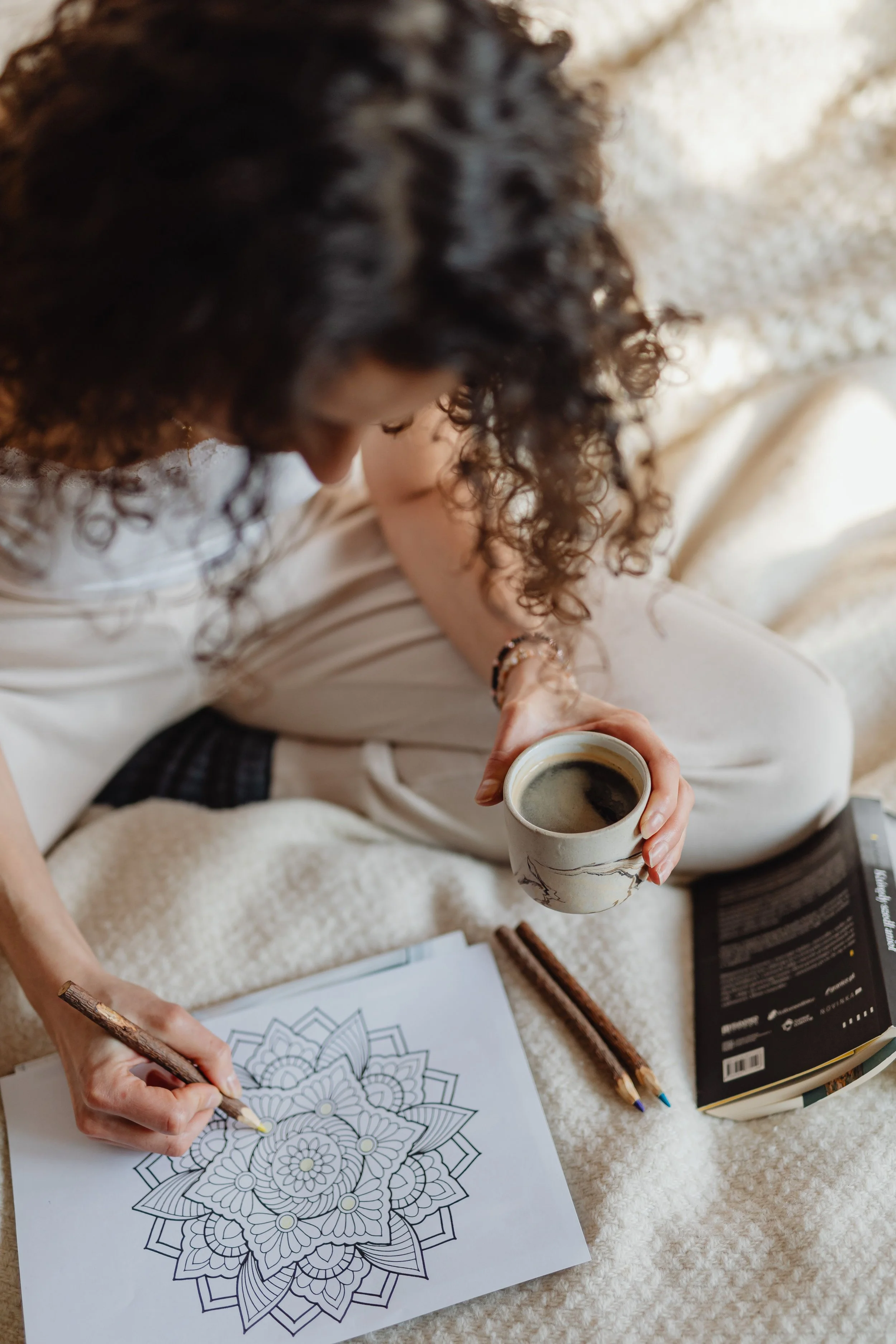 Woman colouring on bed and holding coffee cup