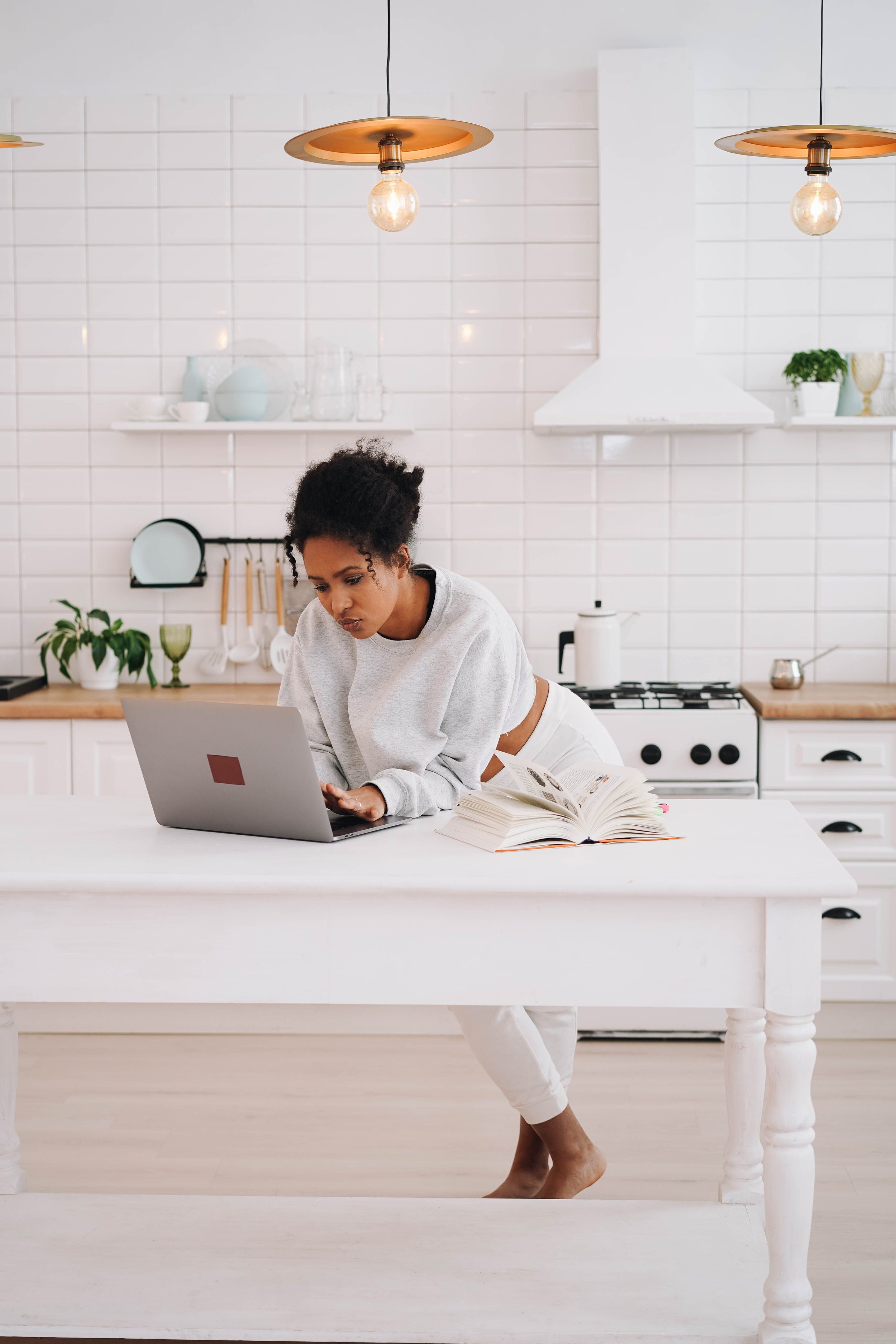 Black woman on working on laptop in kitchen