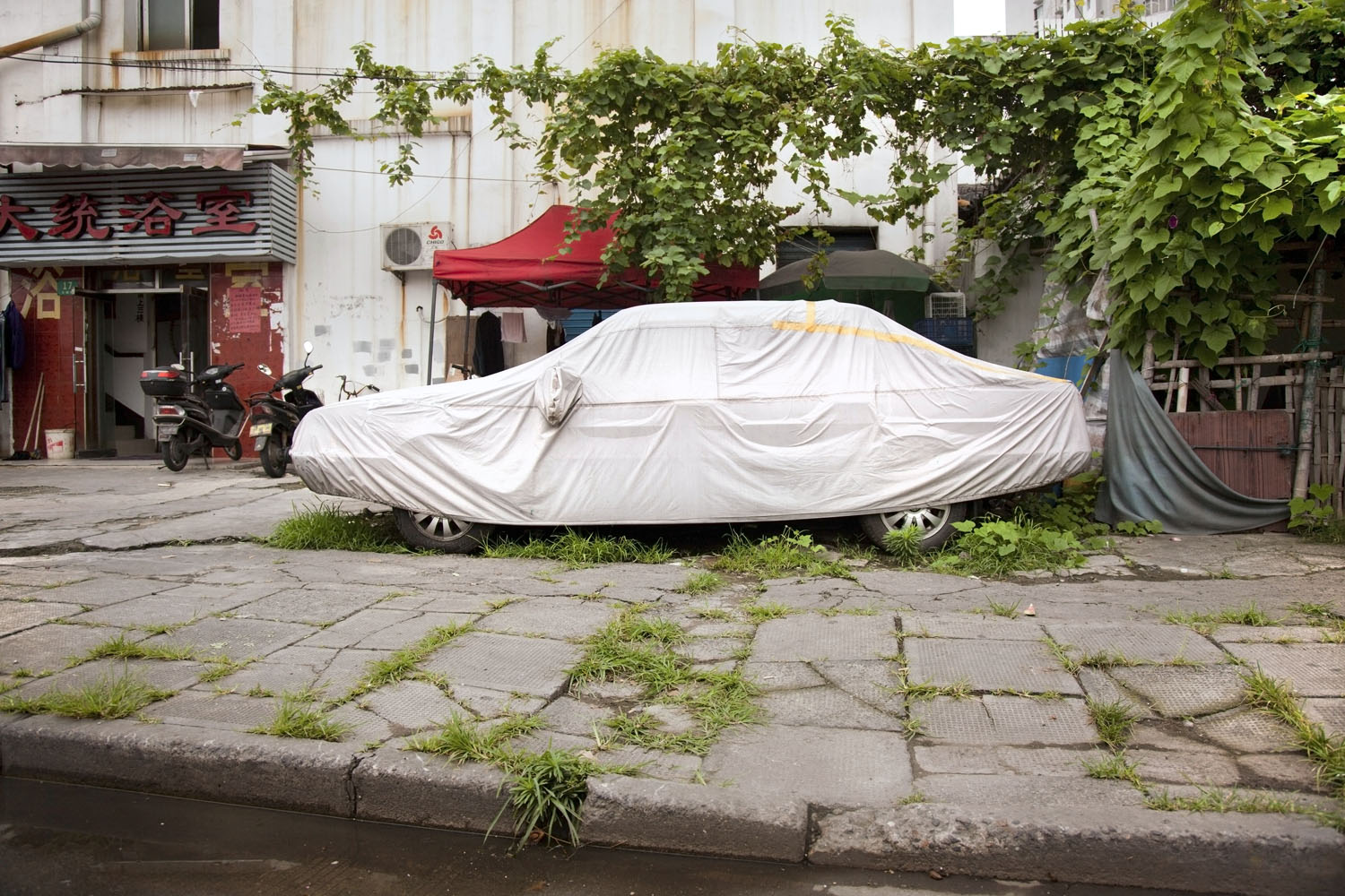 A tarp-covered car parked in an old neighborhood in Huangpu District. Shanghai, China. 2012.