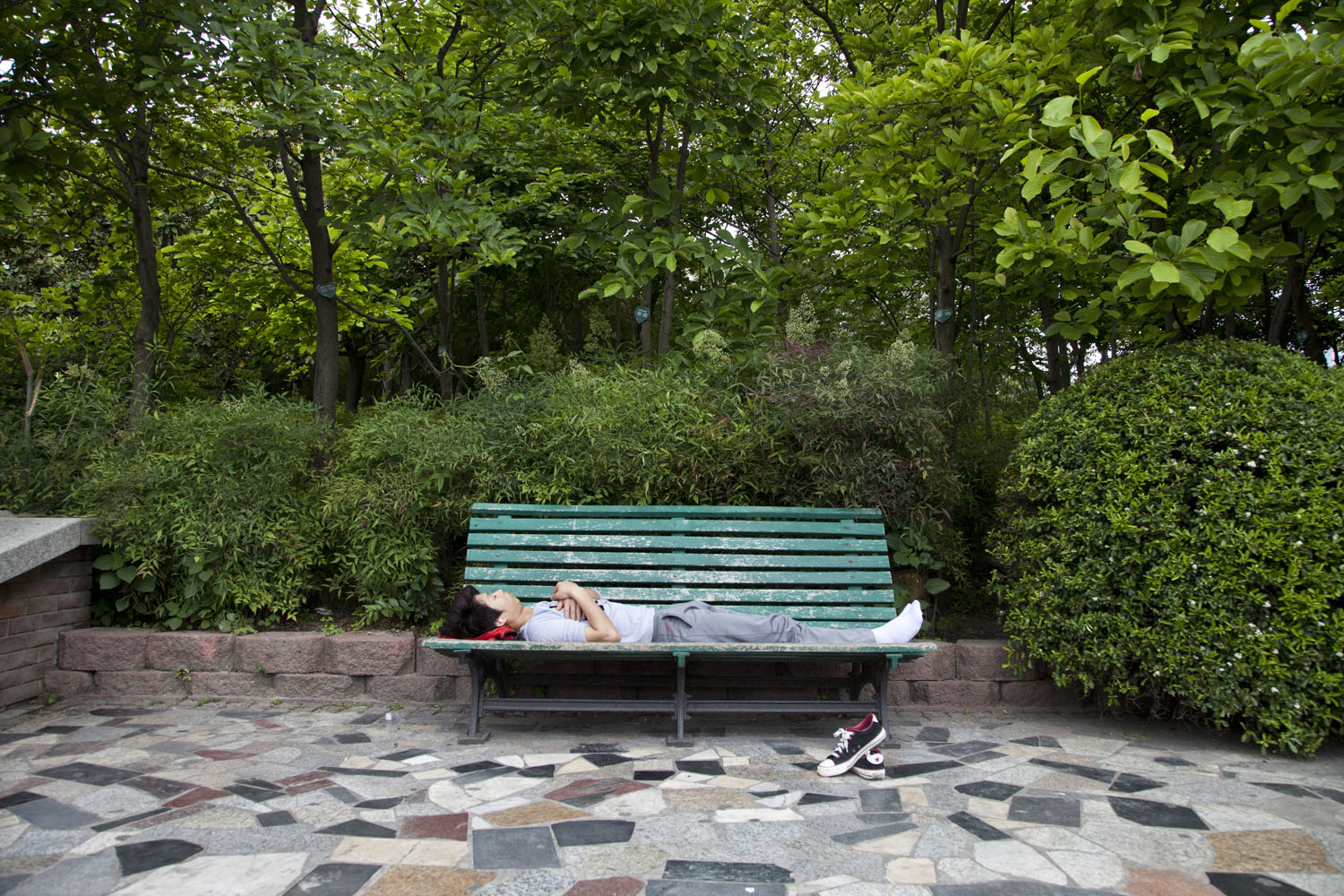 A young man rests on a park bench near West Yan'An Highway. Shanghai, China. 2013. 