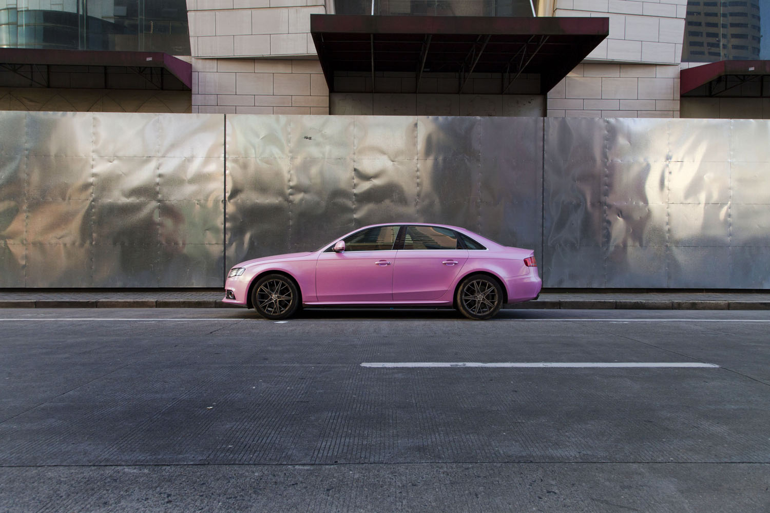 Pink luxury sedan parked in front of a metallic construction wall. Shanghai, China. 2015. 