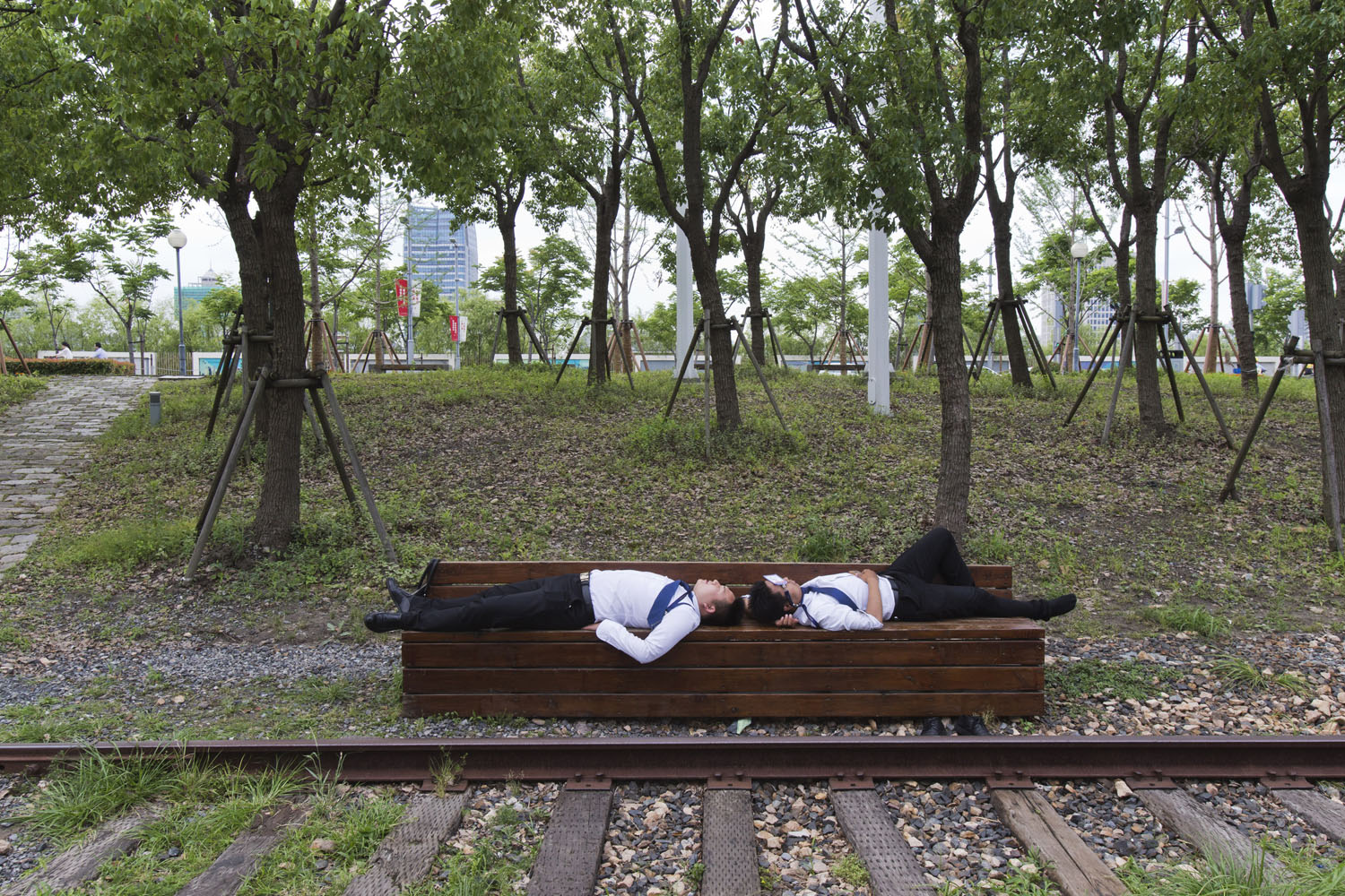 Two men resting on a bench at West Bund. Shanghai, China. 2017.