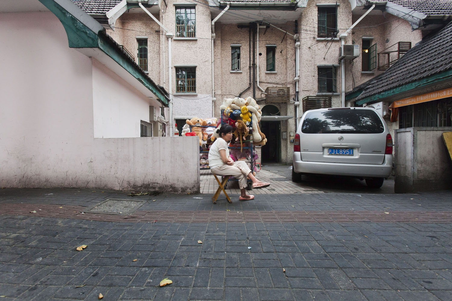 Woman sitting next to carts full of stuffed animals in Changning. Shanghai, China. 2015.