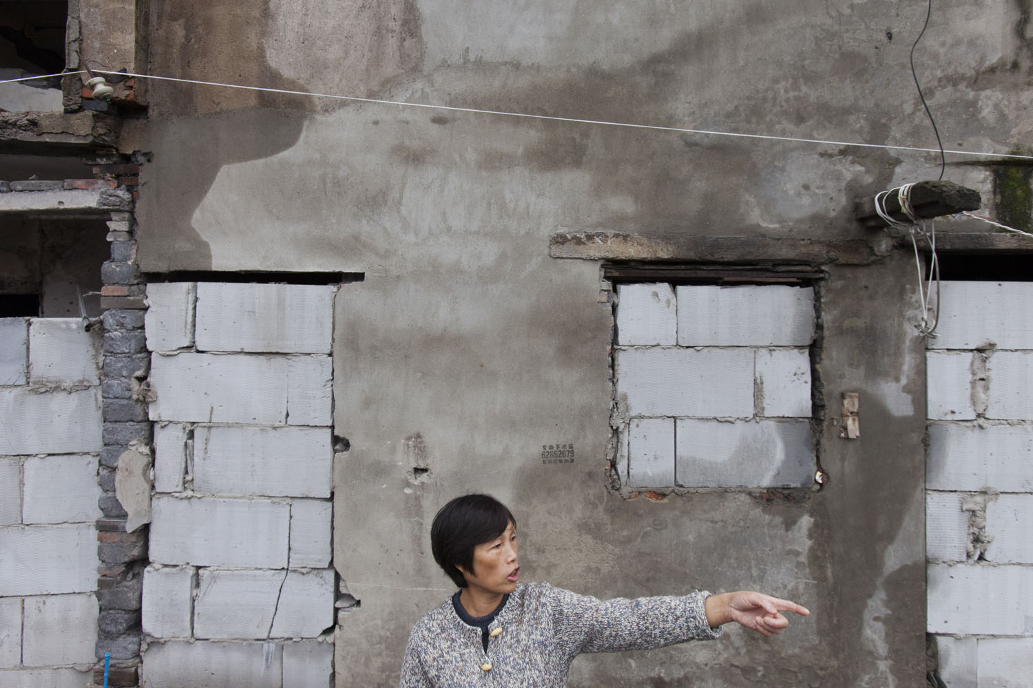   A woman talks to her neighbors in front of condemned property. Guangfu Road. Shanghai, China. 2015.