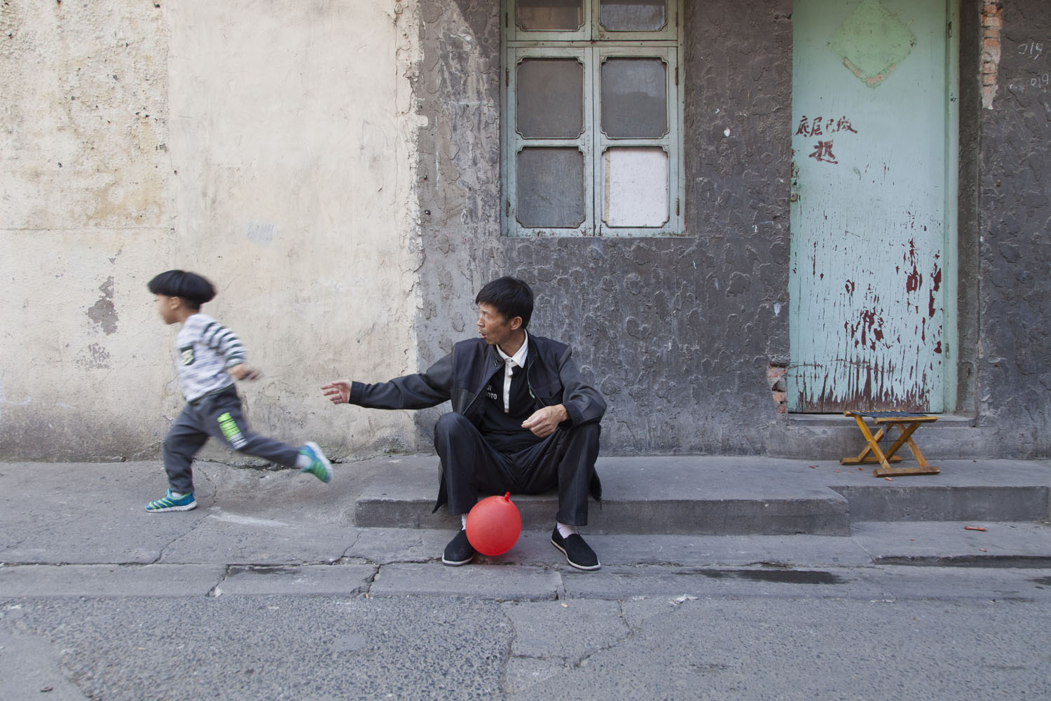   An elderly man and his grandson play in one of the main alleys. Guangfu Road. Shanghai, China. 2015.