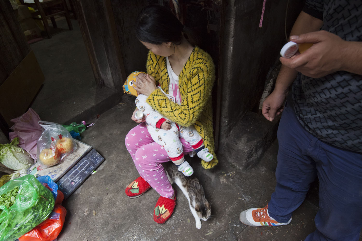   A mother applies cream to her child's face outside of their room. Guangfu Road. Shanghai, China. 2015.