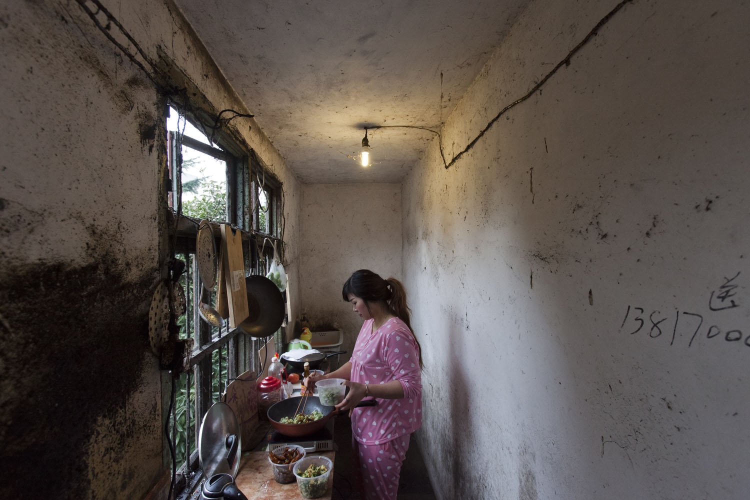 Woman prepares a lunch in a shared kitchen adjacent to her rented apartment. Guangfu Road. Shanghai, China. 2015.