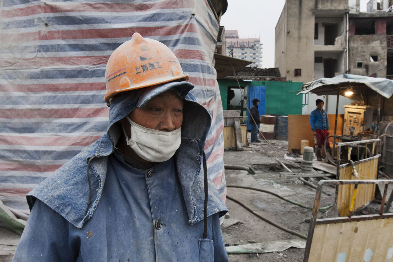 Migrant laborer watches cement being poured. Guangfu Road. Shanghai, China. 2015.