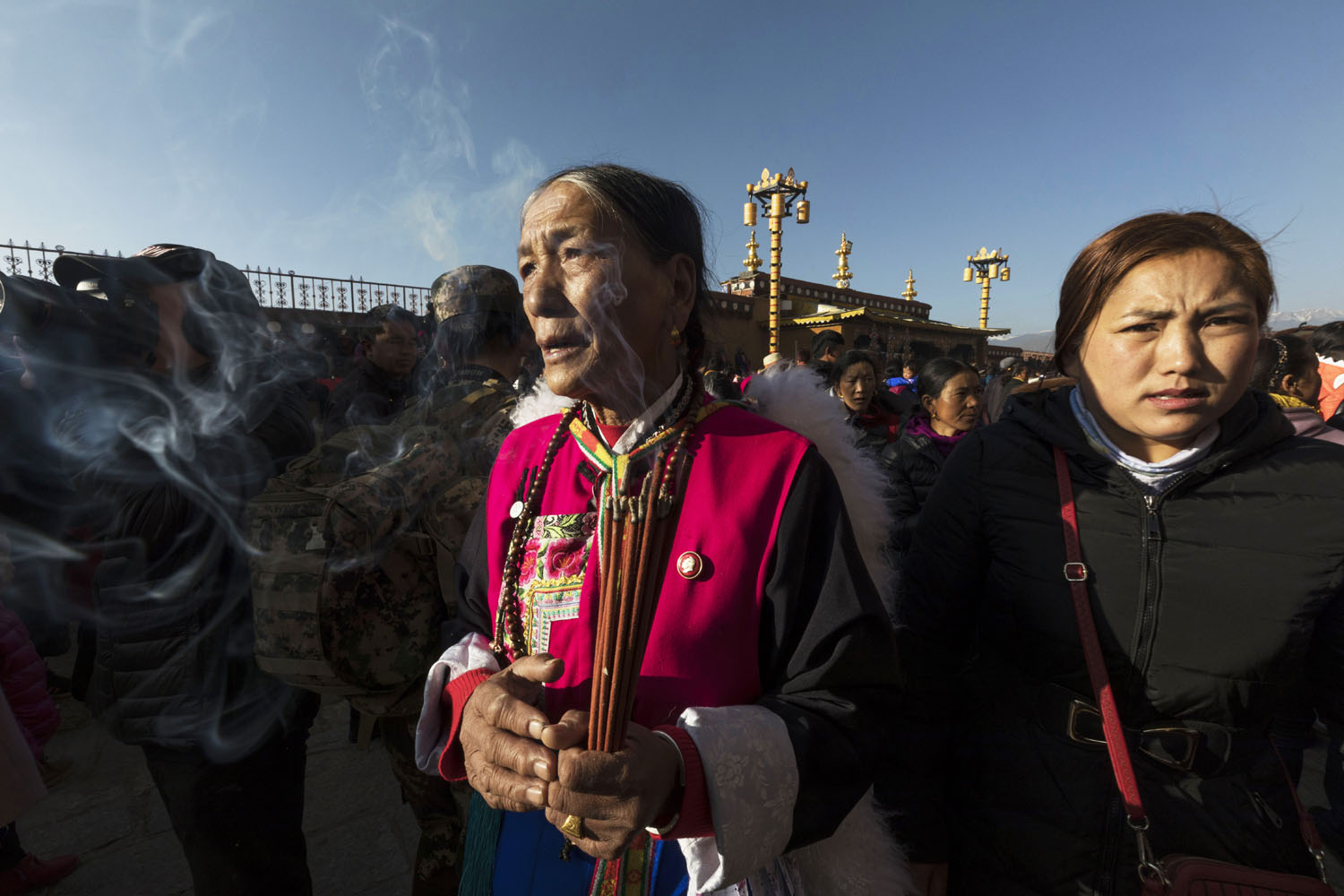 Woman dressed in traditional Tibetan clothing chants while holding burning incense at SongZangLin Monastery in JingXiang Village. Yunnan, China. March 2, 2018.