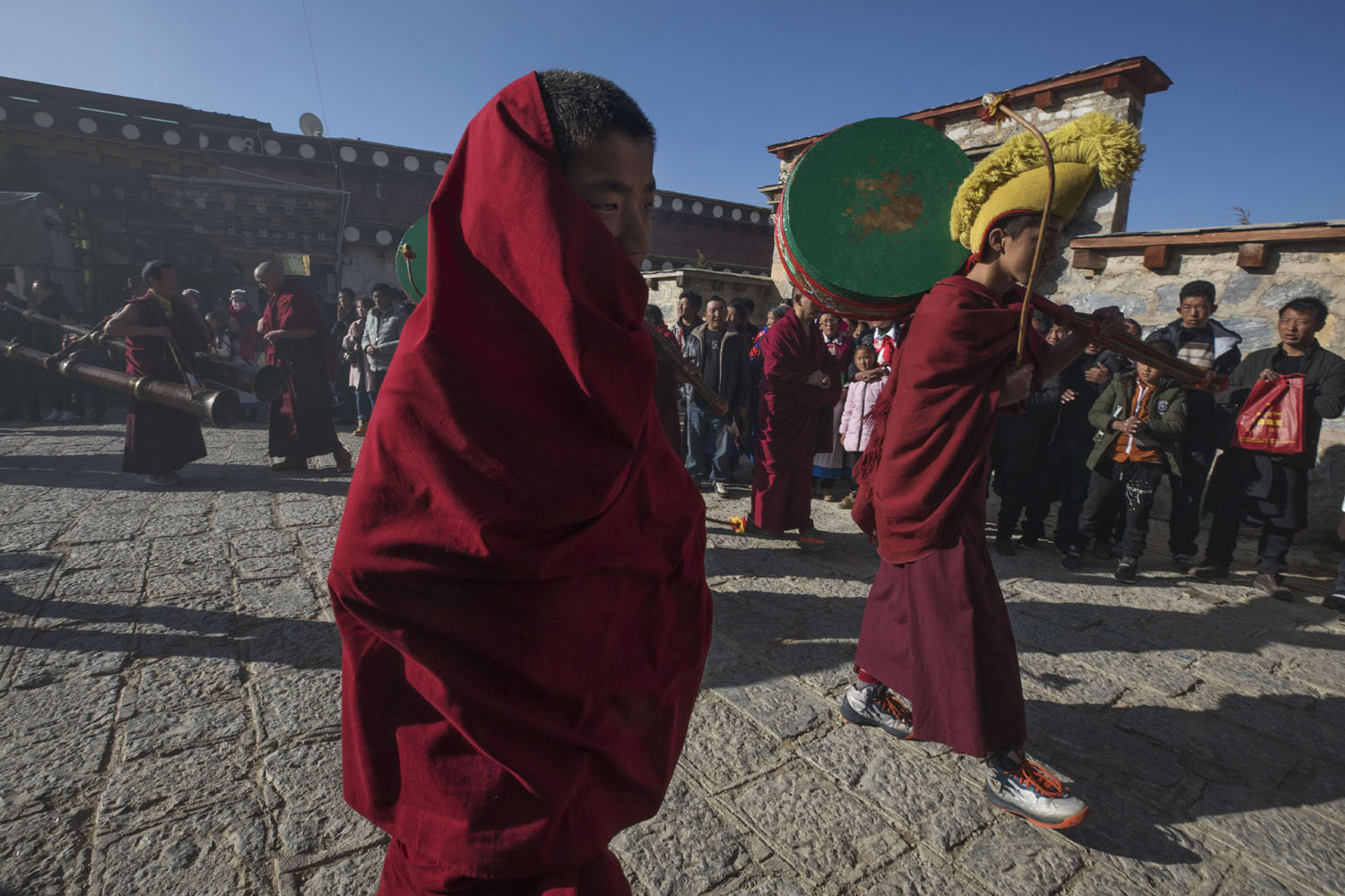 Tibetan Buddhist monks carry instruments at the start of the parade that travels through JingXiang Village, at SongZangLin Monastery. Yunnan, China. March 2, 2018.