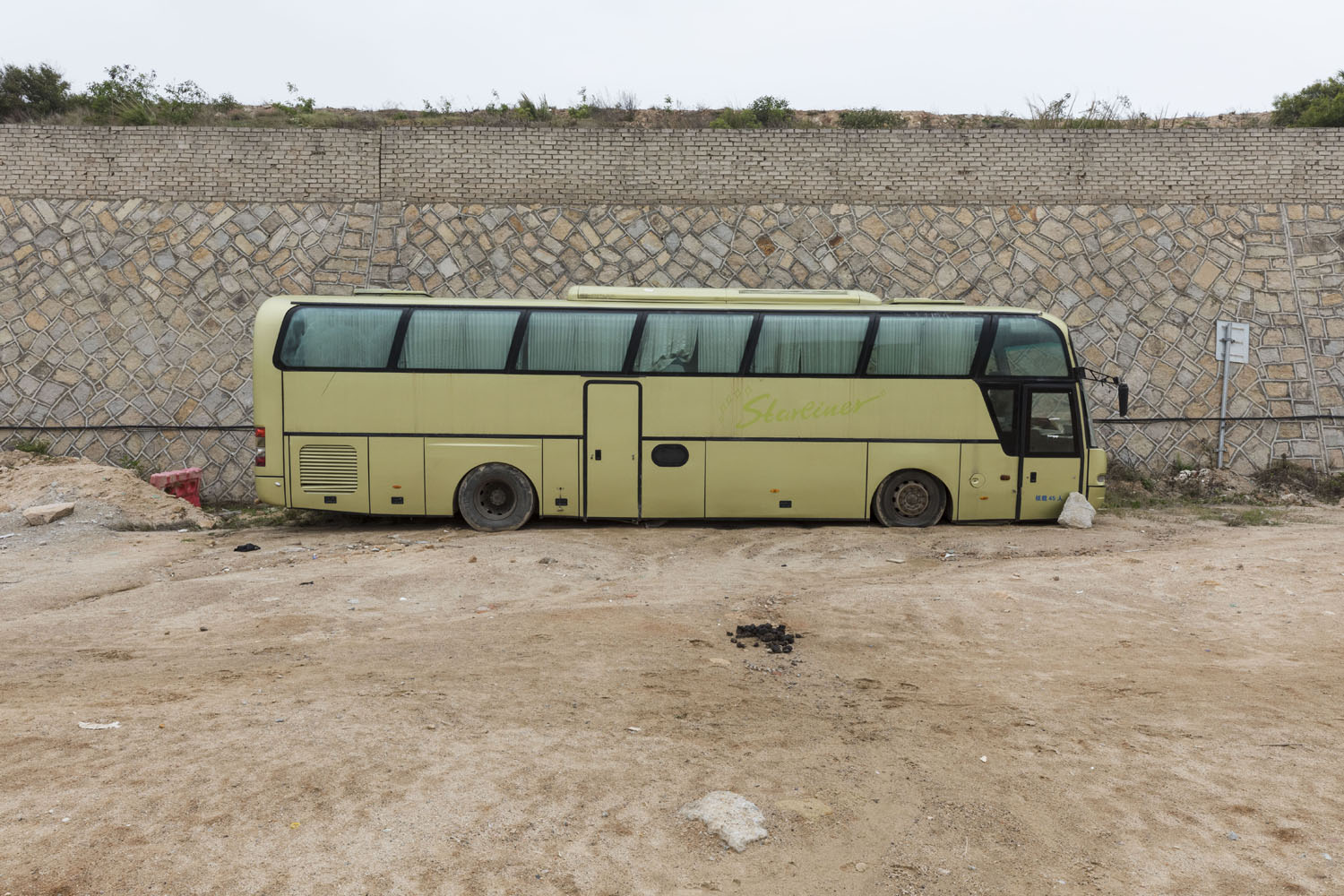 Bus sits along a barrier wall at Guanyinshan Fantasy Beach. Xiamen, China. 2018.