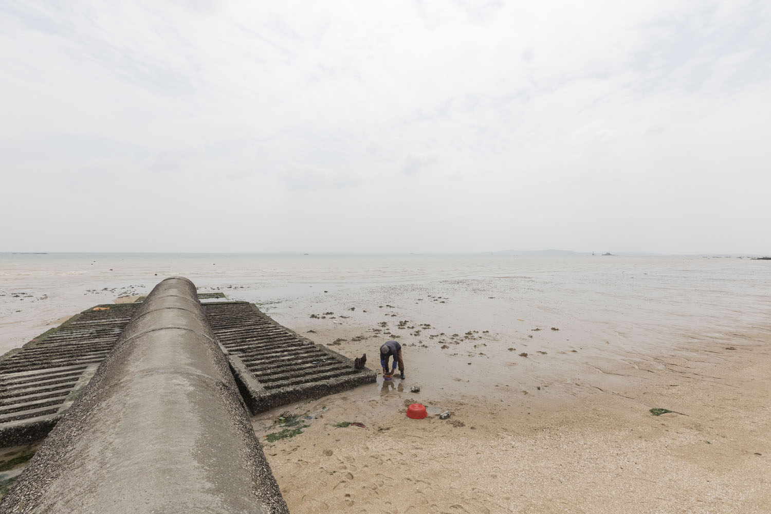 Man sifts through sand searching for shellfish at Guanyinshan Fantasy Beach. Xiamen, China. 2018.