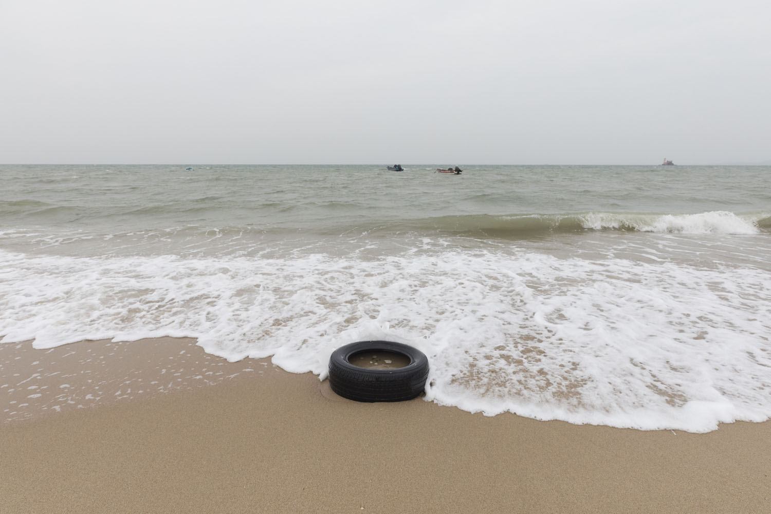 A tire along the shoreline at Guanyinshan Fantasy Beach. Xiamen, China. 2018.