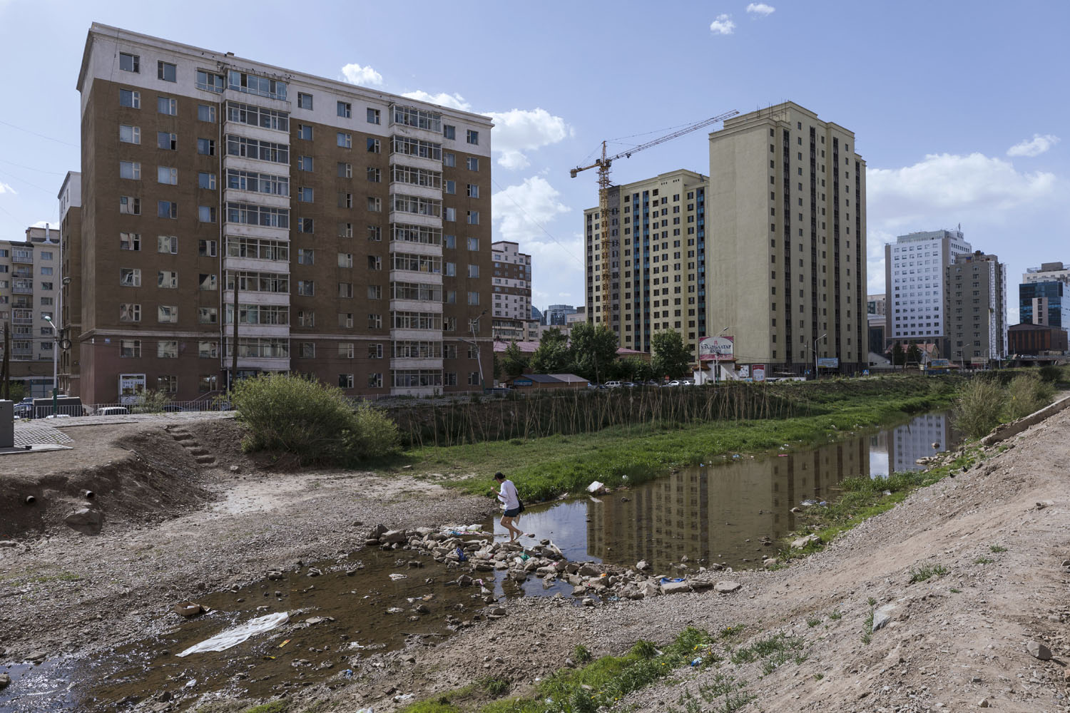 A woman crosses the Selbe River. Ulaanbaatar, Mongolia. 2018.