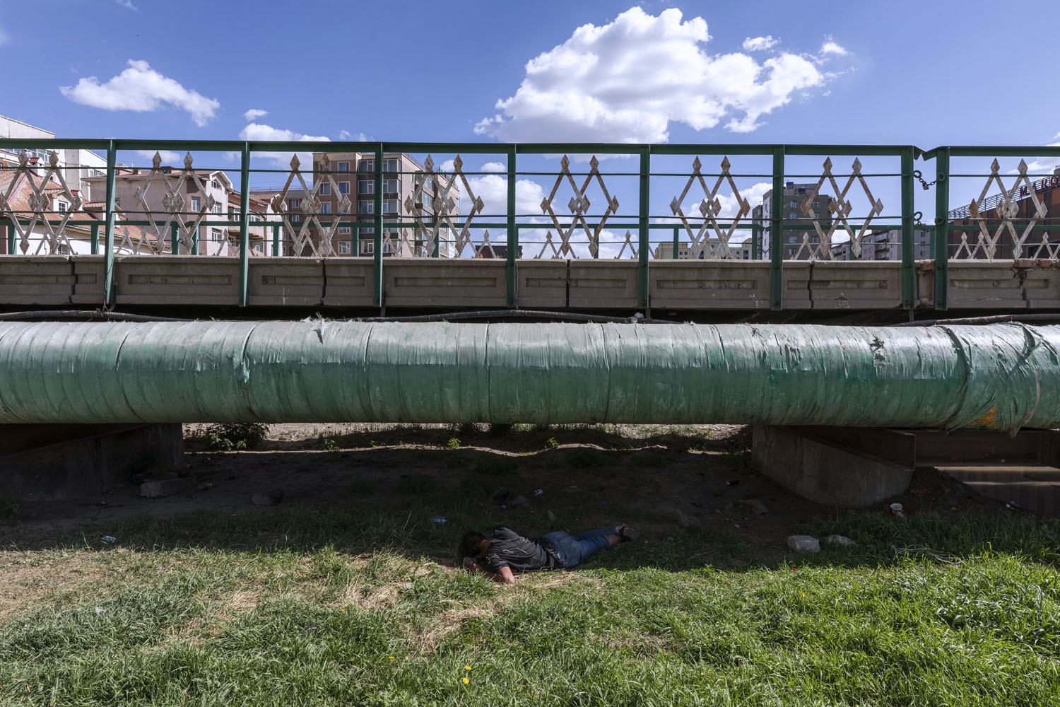 Man sleeps beneath a pedestrian bridge that crosses the Selbe River. Ulaanbaatar, Mongolia. 2018.