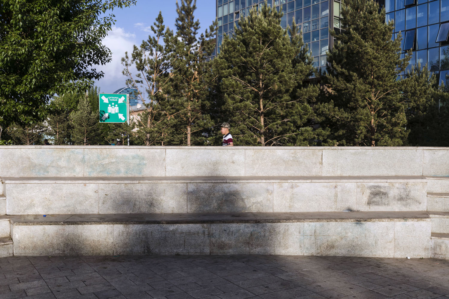 Child walks along the edge of a concrete structure in a park, in downtown Ulaanbaatar. Ulaanbaatar, Mongolia. 2018.