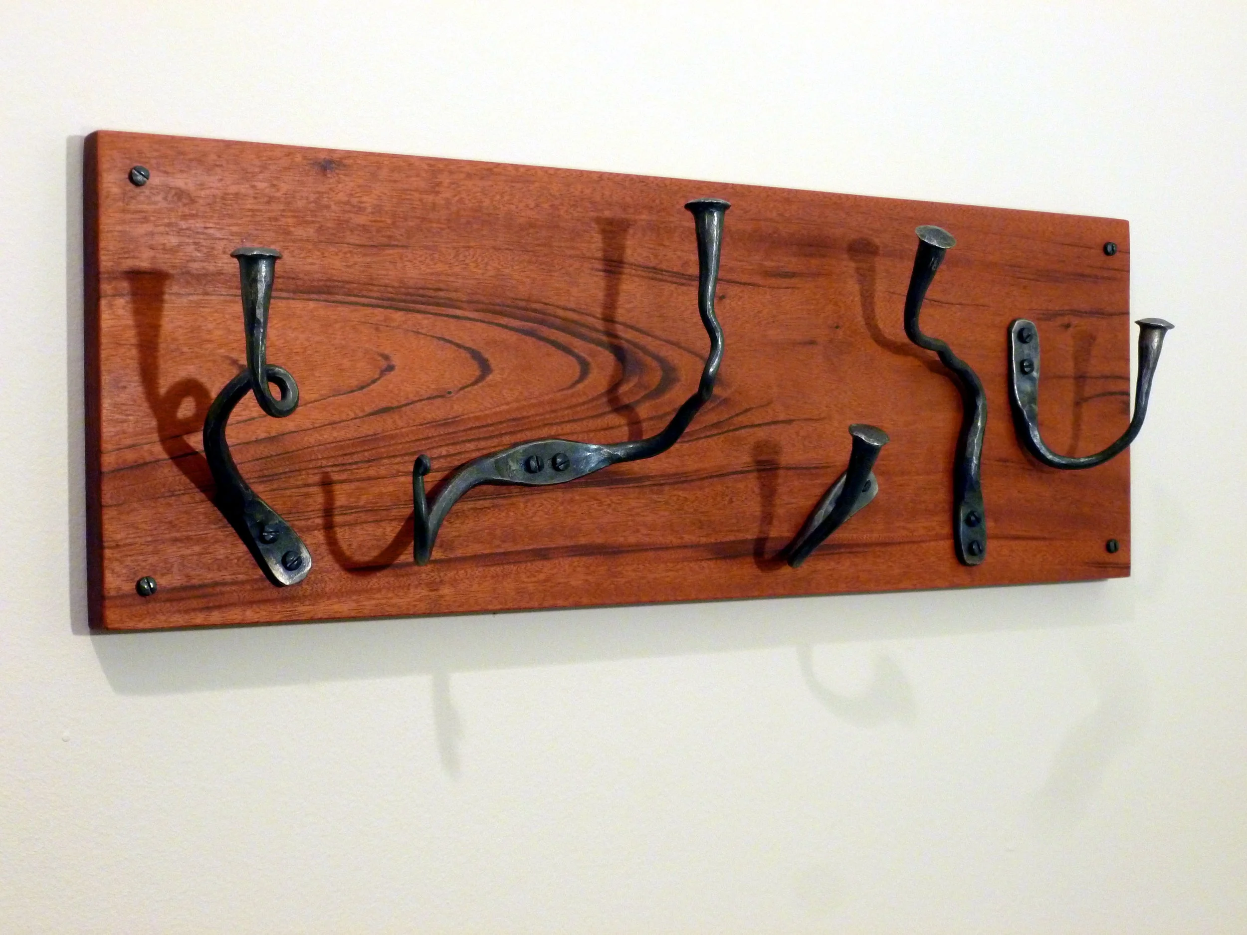 Forged coat hooks mounted on mahogany