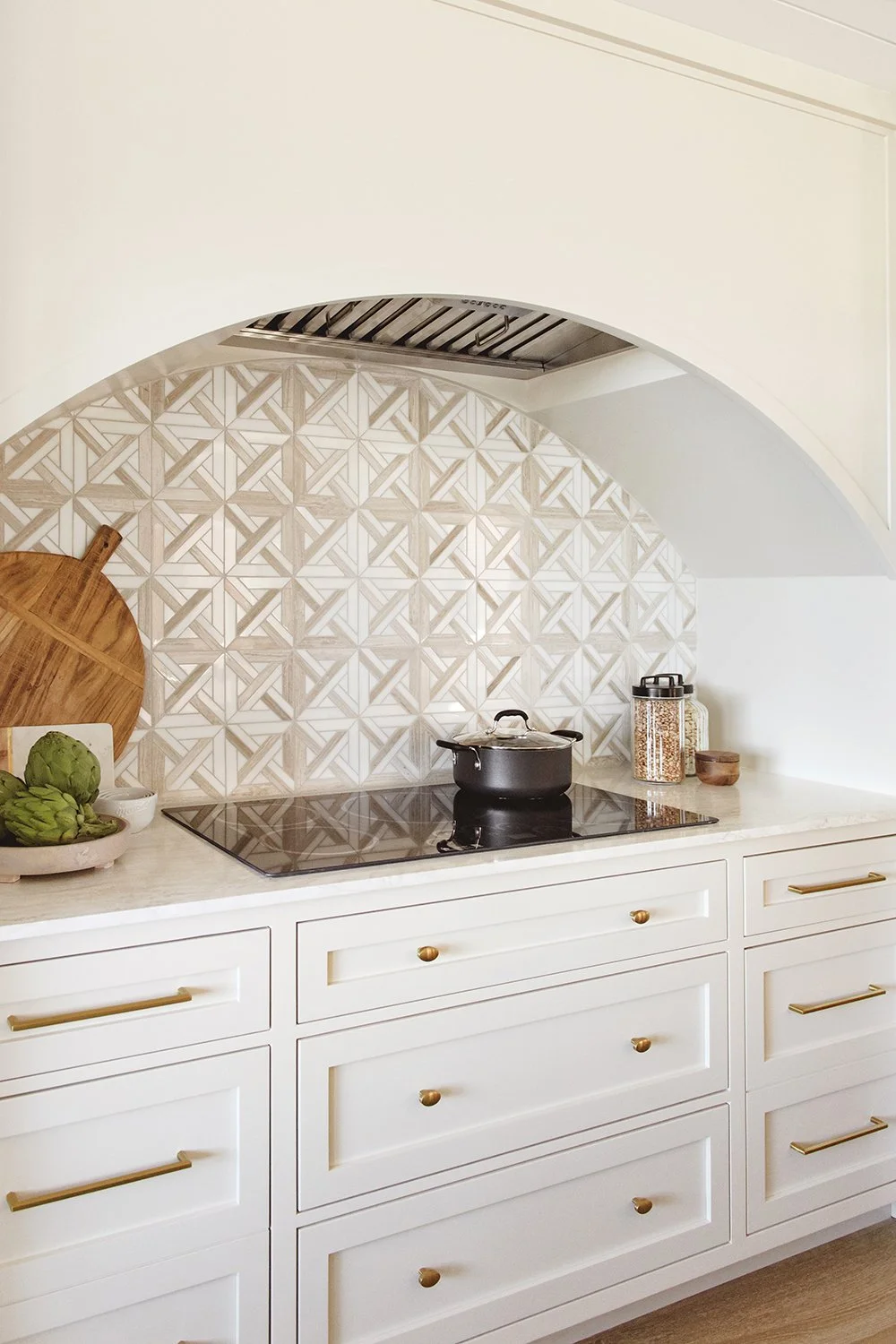 Arched kitchen alcove with geometric tile backsplash, custom white cabinetry, and matte black faucet in a full home remodel by Savvy Interiors in Del Mar, North County San Diego.