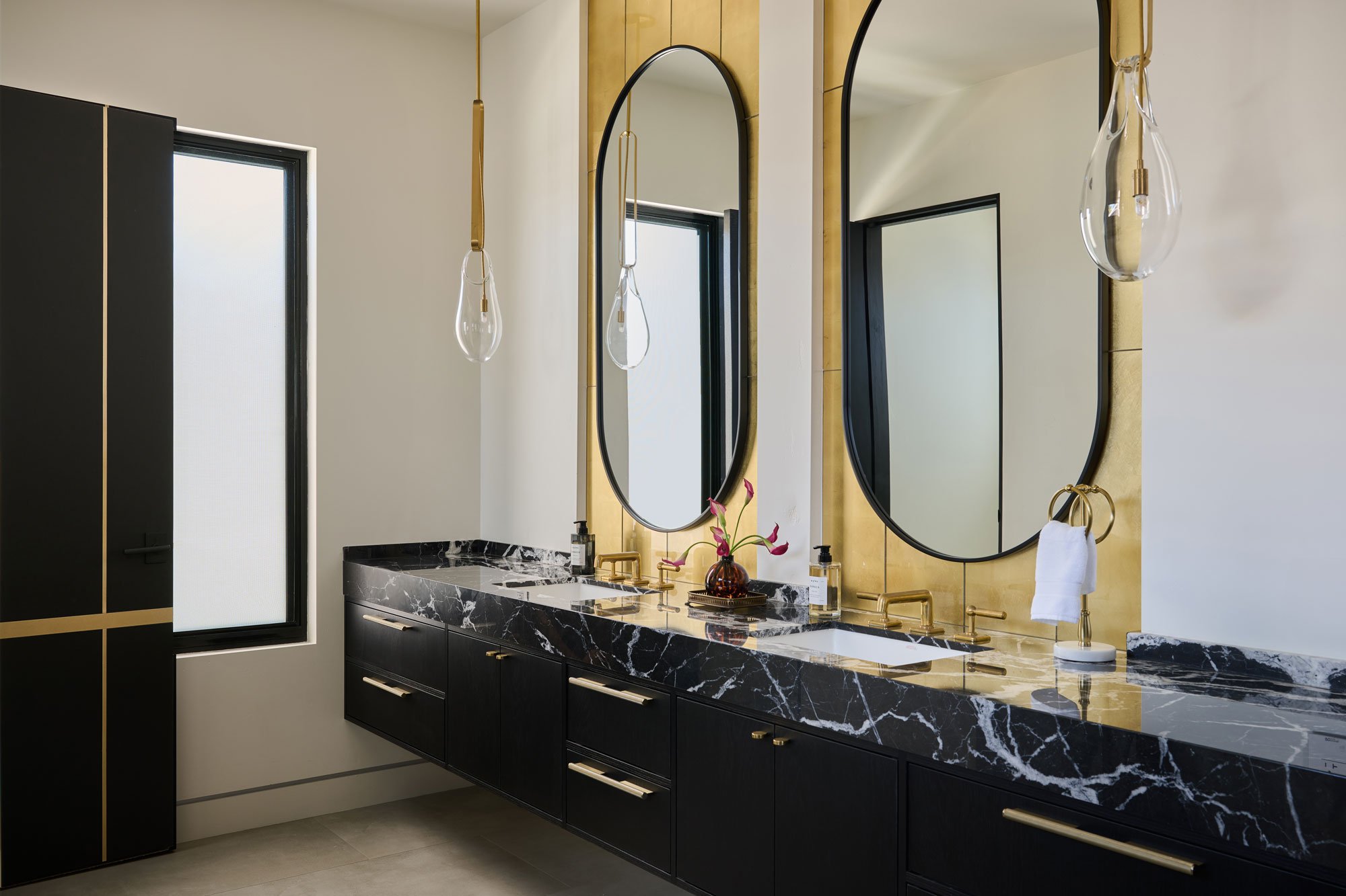 Modern bathroom remodel with custom double vanity, stone countertops, and brass fixtures in a San Diego home by Savvy Interiors