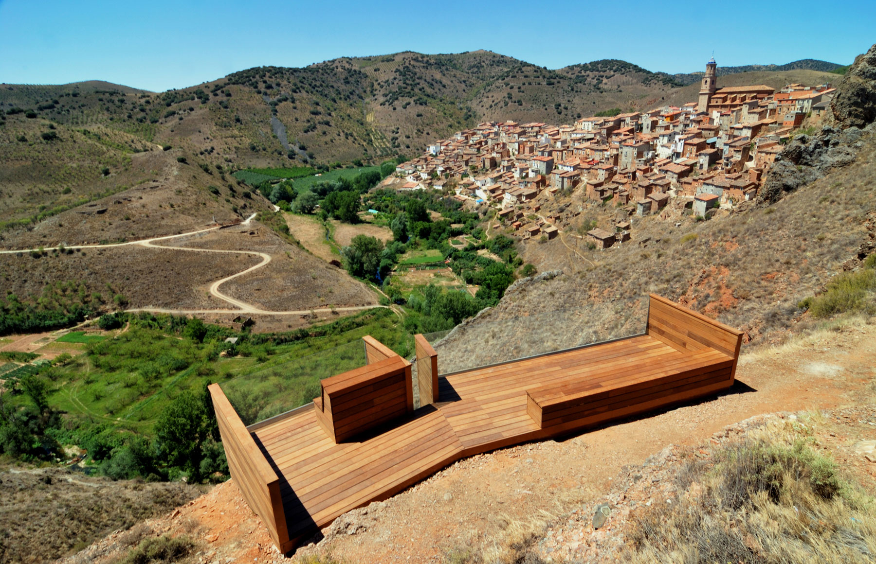 Starting from the establishment of an outdoor space, an easy way to perceive the landscape is created, a comfortable and almost domestic place like the balcony of a house, where you can contemplate this characteristic and unique picture: a patchwork of houses which are attached and twinned as a cubist painting, being scattered along the side of the hill to the fertile Manubles Valley. 