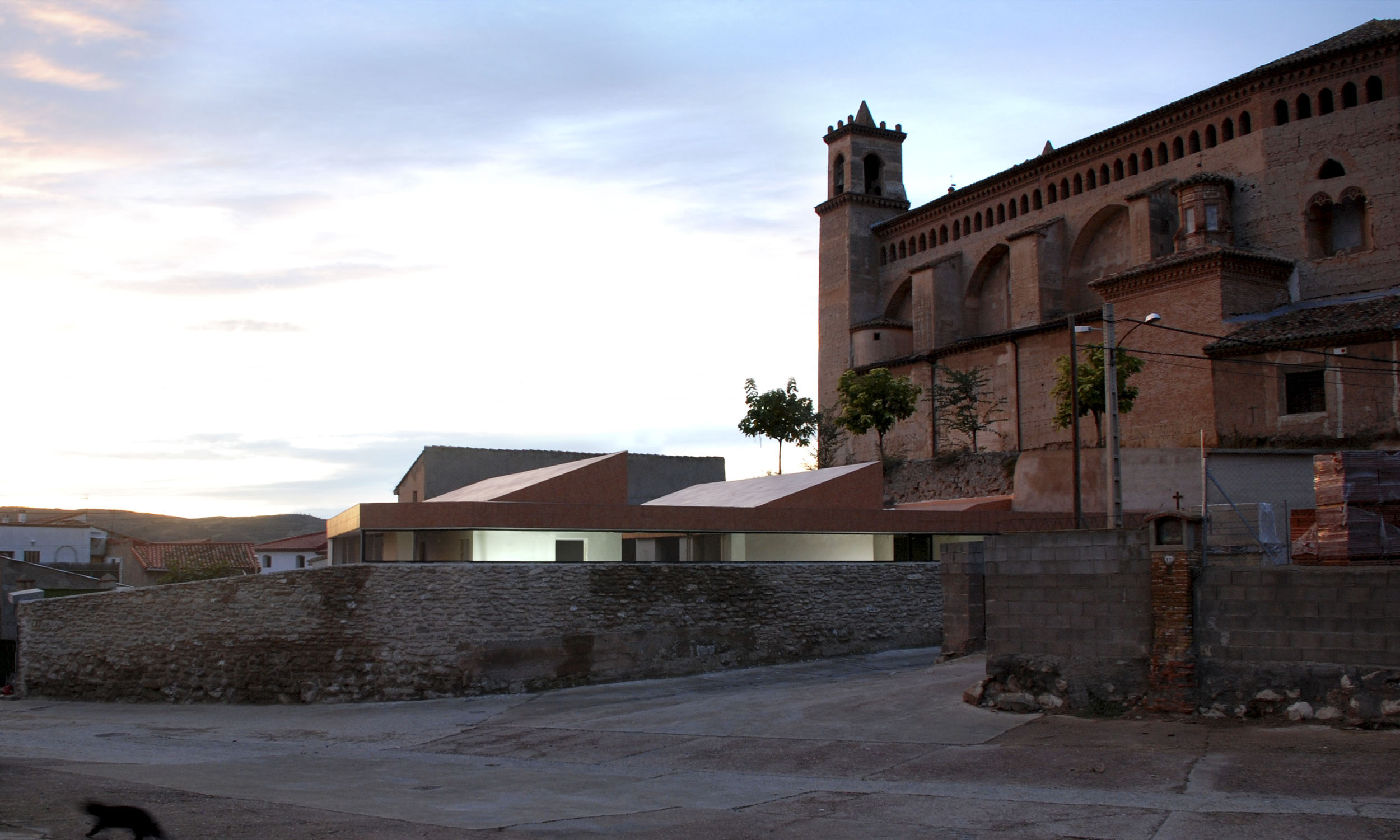 The house of Fernando and Tania stems from the respect to the elements which are nearby, surrounding that place. Its location, in the limit of the historical centre of Maluenda, in a site which lies below the feet of the Mudéjar church of Santas Justa and Rufina – dominant shape of the village-, whose stone wall surrounding was part of the ancient wall, was fundamental in the conception of the project. Beneath the roof, the house is deployed in a single storey, creating a unique world of references inside, throughout patios, and making visual connections with the exterior, from raised holes which focus the interest in the most relevant points nearby.