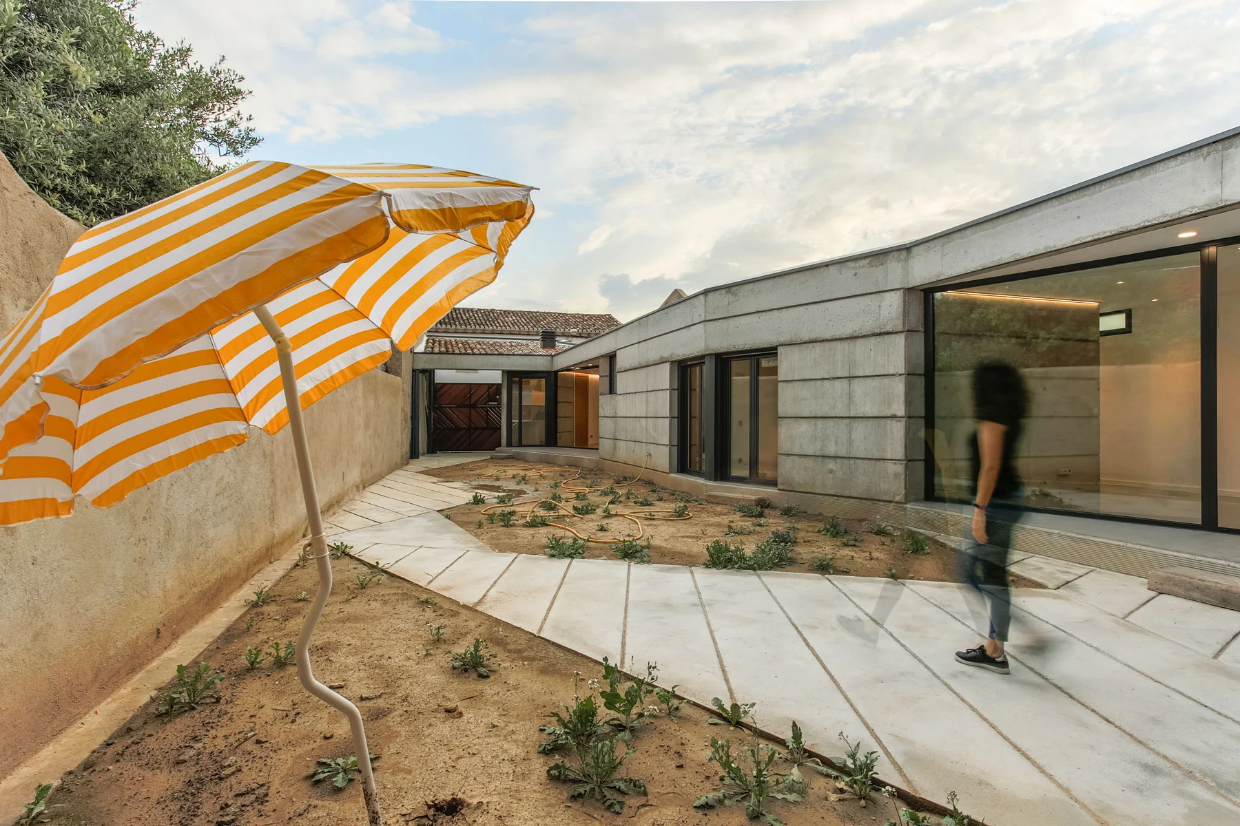 Without renouncing its time and its function, MM House is located in the urban center of Leciñena as a new enclosure, trying to keep the idea of unity and balance with existing buildings, respecting the traditional and material values but in a contemporary key. The urban context is made up of narrow and long lots, with the part usually built on the side of the road and with free plot on the bottom, for vegetable gardens and animal enclosures, in which some smaller buildings are usually placed against the walls, to make them more stable. One of the clients' requests was to be able to enjoy the house as much as the outside space, creating a very close relationship between home and patio. Therefore the volume is all set against the North wall and opens completely to the outer space, and interacts with the patio, which, in turn, is nothing but the same road that bends and enters through the entrance and, from the ground cemented, it becomes a private garden
