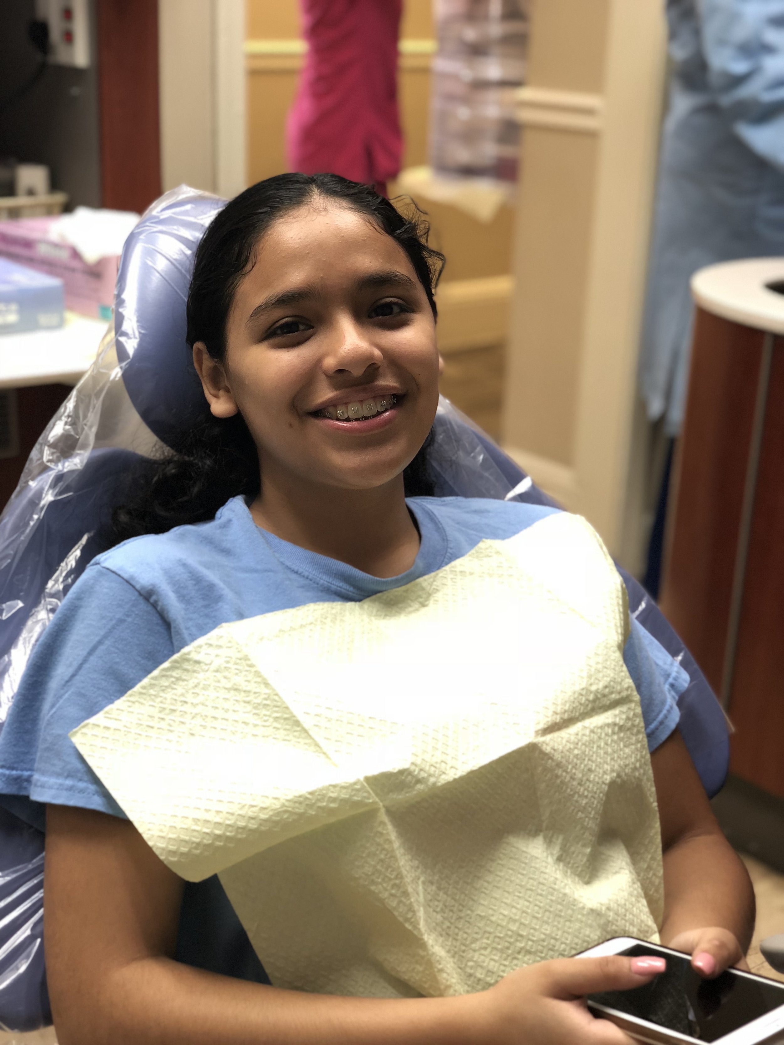 Patient sitting up in a dental chair smiling at the camera 