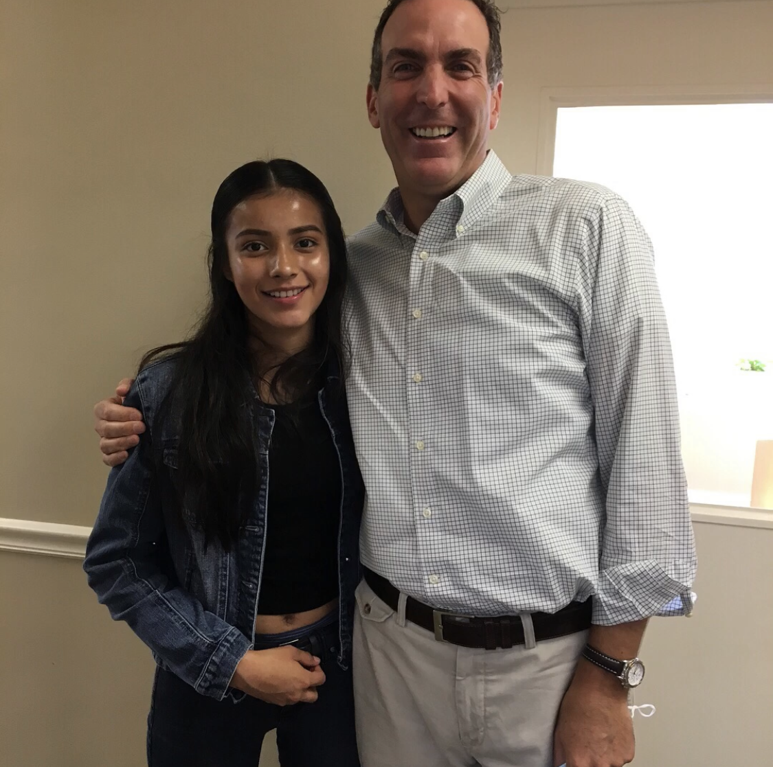 Doctor Gerlein stands next to a patient with his arm around her. They are both smiling at the camera 