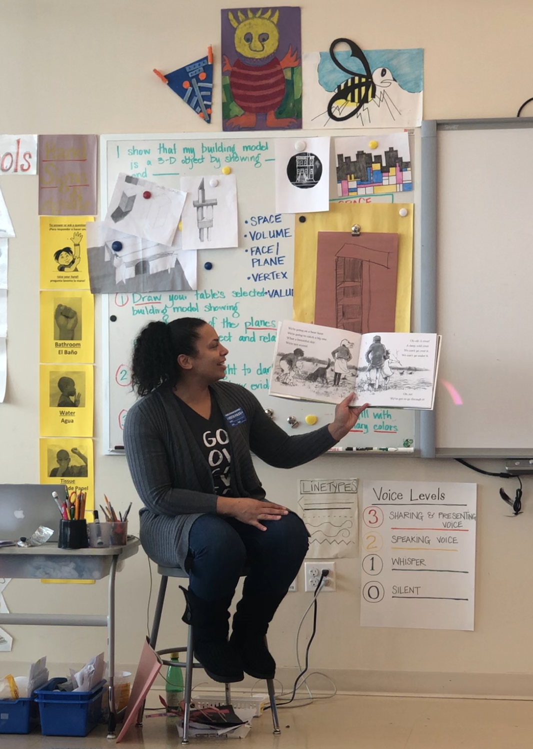 Gerlein team members holds up a picture book and reads to students.