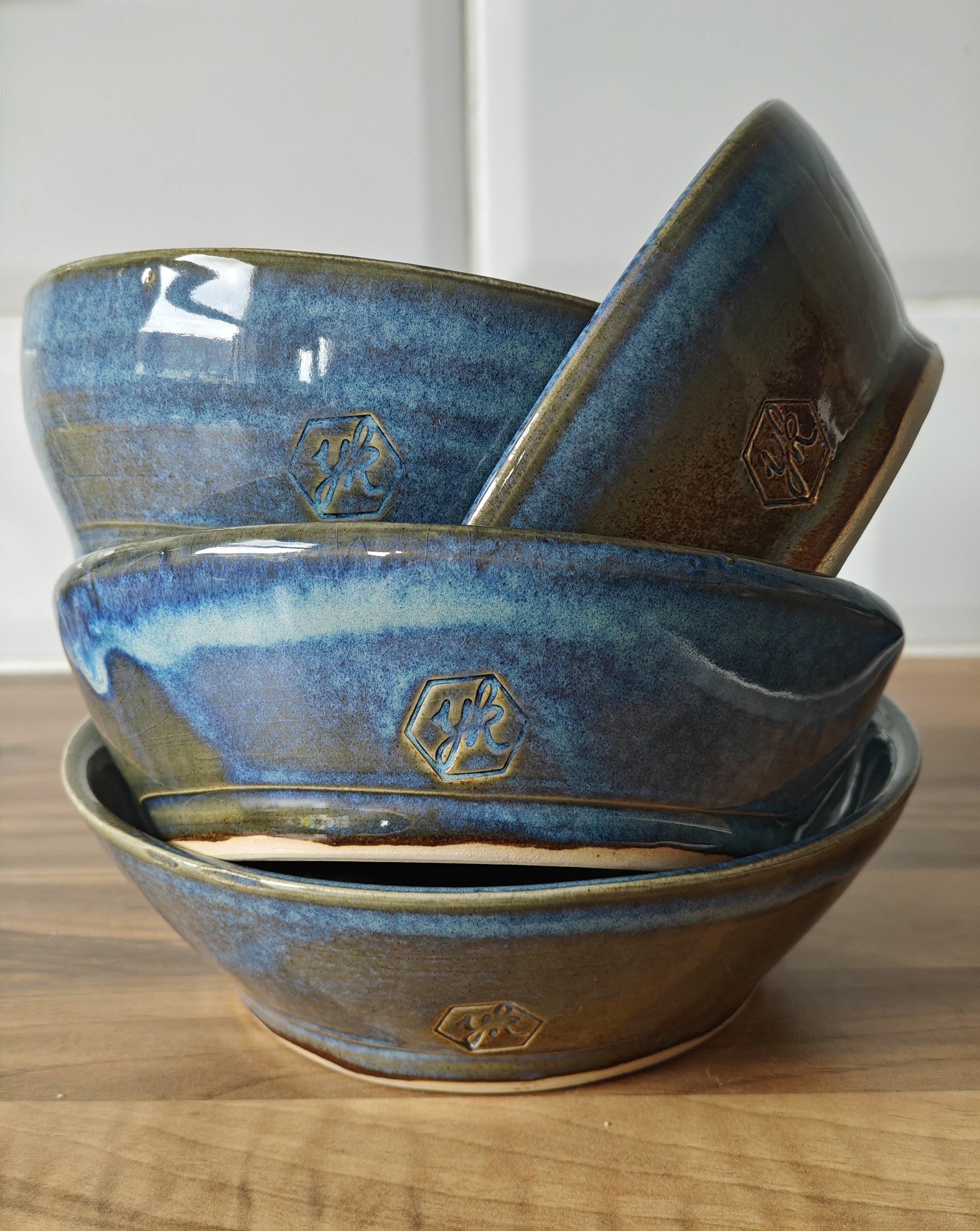 4 blue, handmade ceramic bowls tumble stacked inside each other.