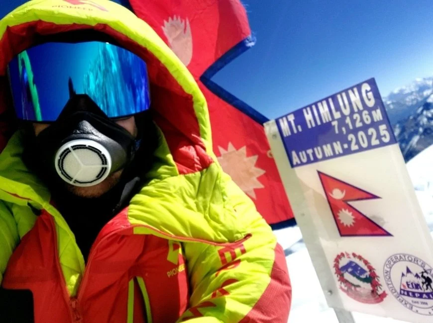 photo selfie d'un alpiniste au sommet de l'himlung Himal avec le panneau indiquant le sommet