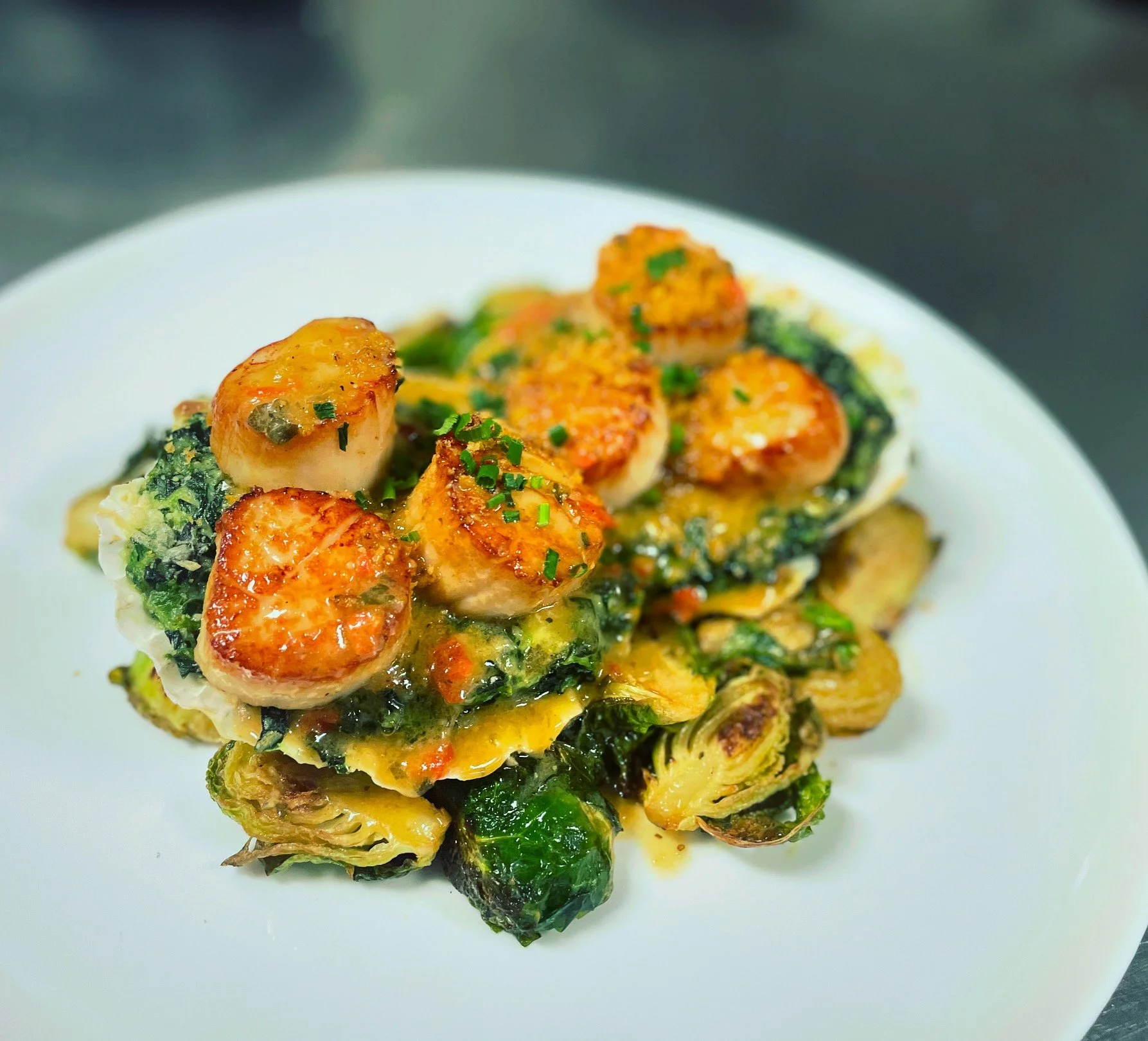 Oyster with spinach, cheese, and herbs on a white plate