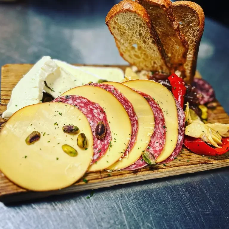 Cheese, salami, and crackers on a wooden board