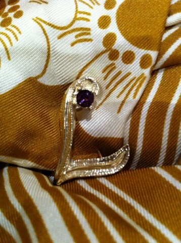 My mother's little initial pin with amethyst stone ... currently pinned to the coat on one of my daughters.
