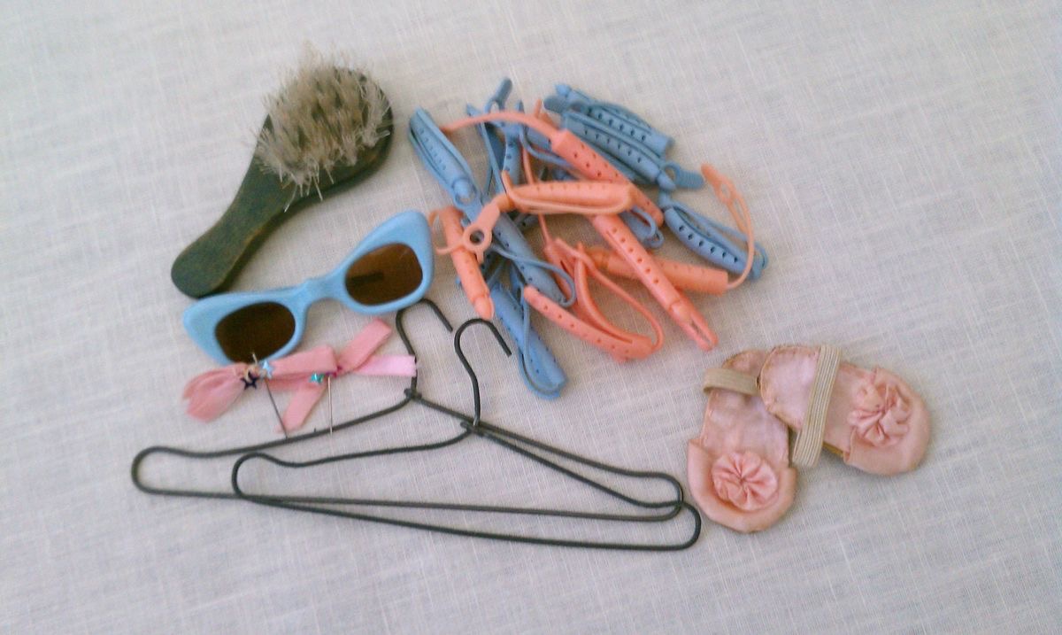 Hair brush and rubber curlers ... two small hangers ... tiny blue sunglasses. My mother made the tiny hair bows to wear with the pink satin gown and the tiny pink slippers were made to wear with the pink print night gown.