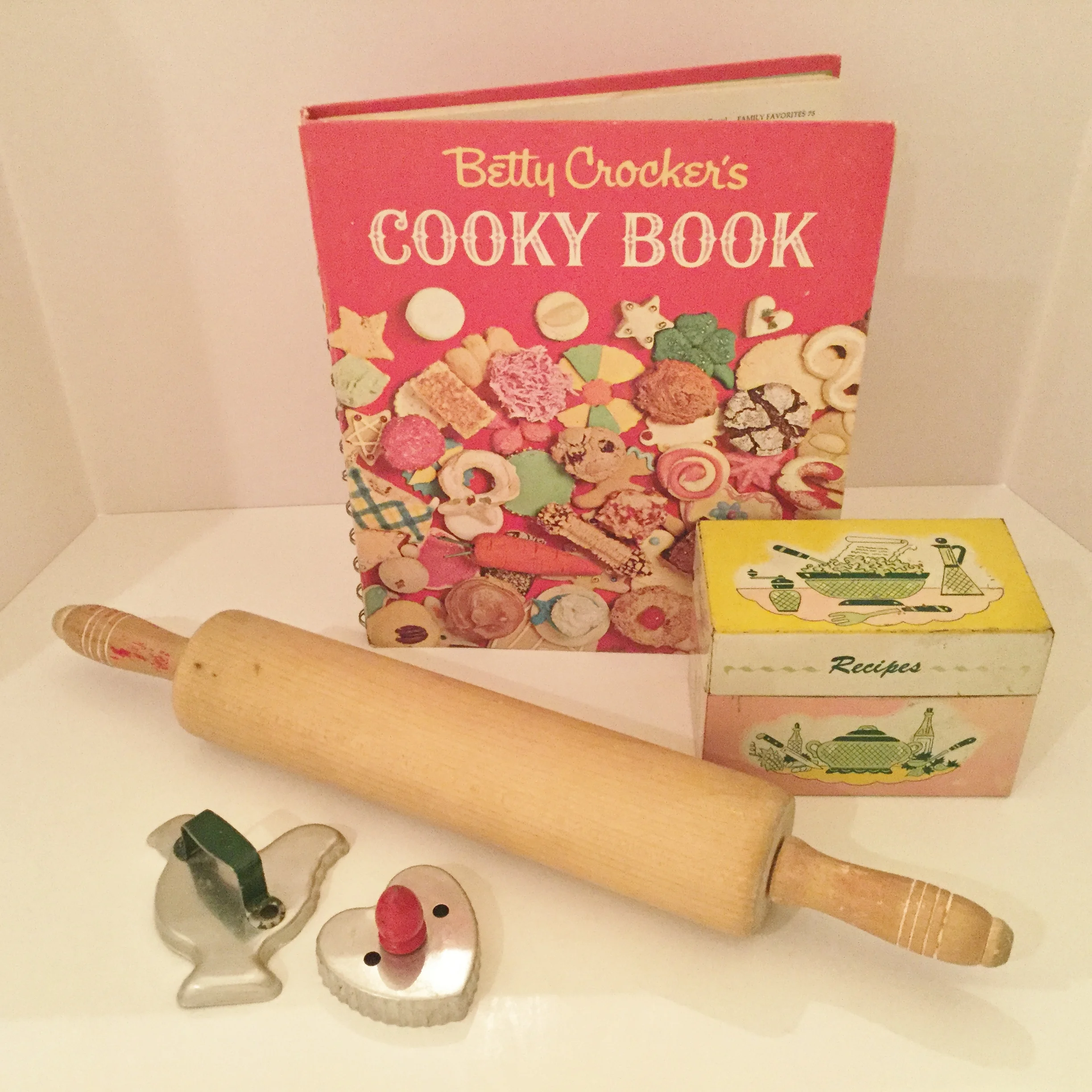 The Betty Crocker Cooky Book was published in 1963 and has been reproduced in recent years. I have both a reproduction (which I bought first) and later I found a first edition, first printing vintage copy. The rolling pin and green handled chicken cutter were my mothers ... I had a pink recipe box in the 1950s like the one in the photo.