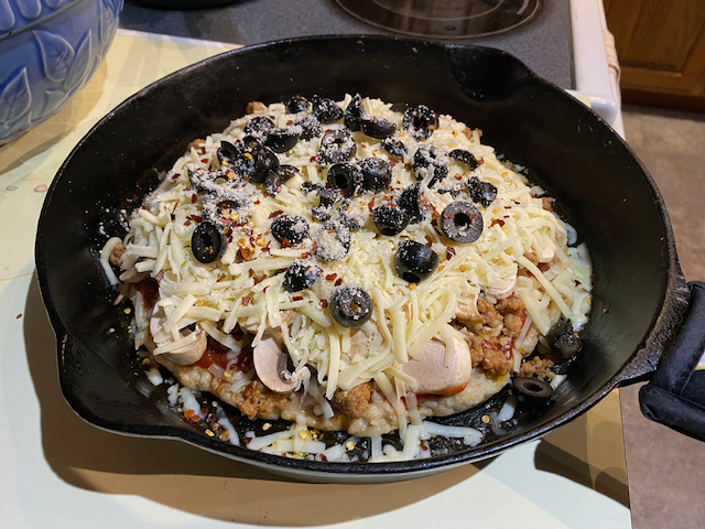 Next is a layer of shredded Monterey Jack cheese, black olives, red chili flakes, and a dusting of parmesan cheese.