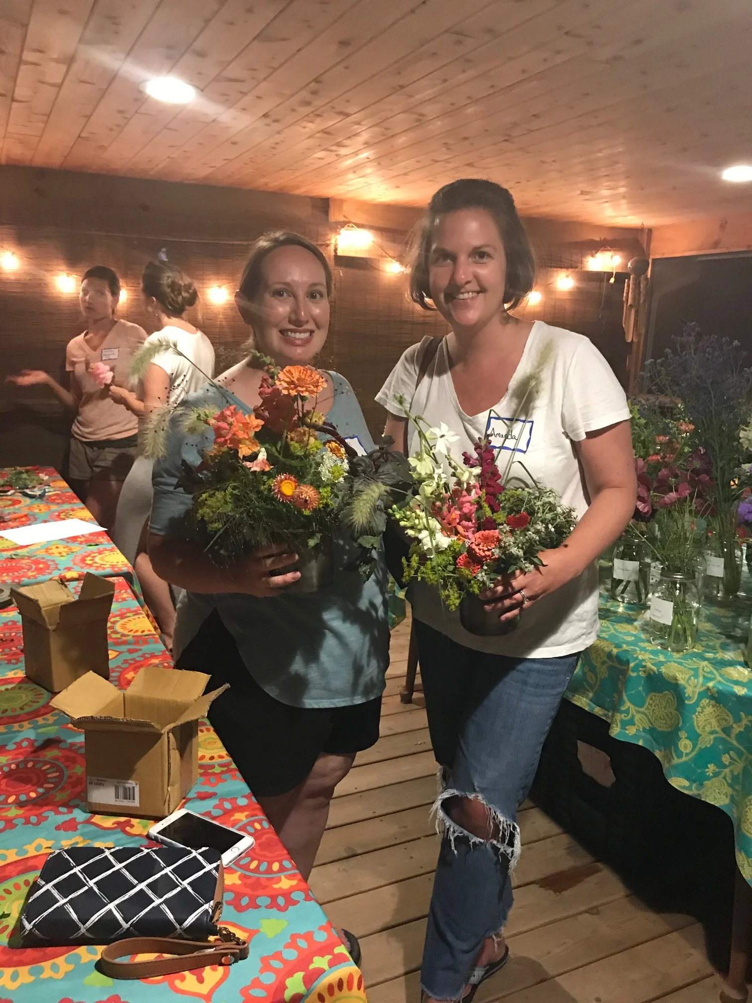 two friends holding their floral arrangements after a workshop