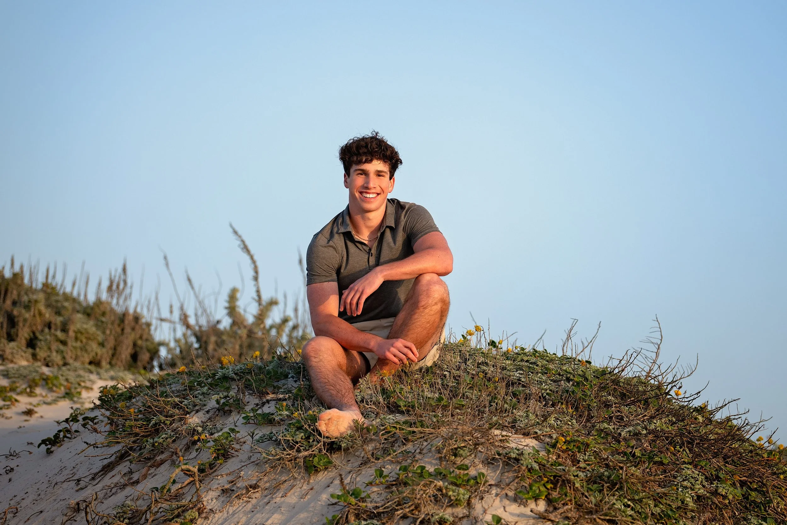 Grant sitting on the top of the sand dunes at sunset