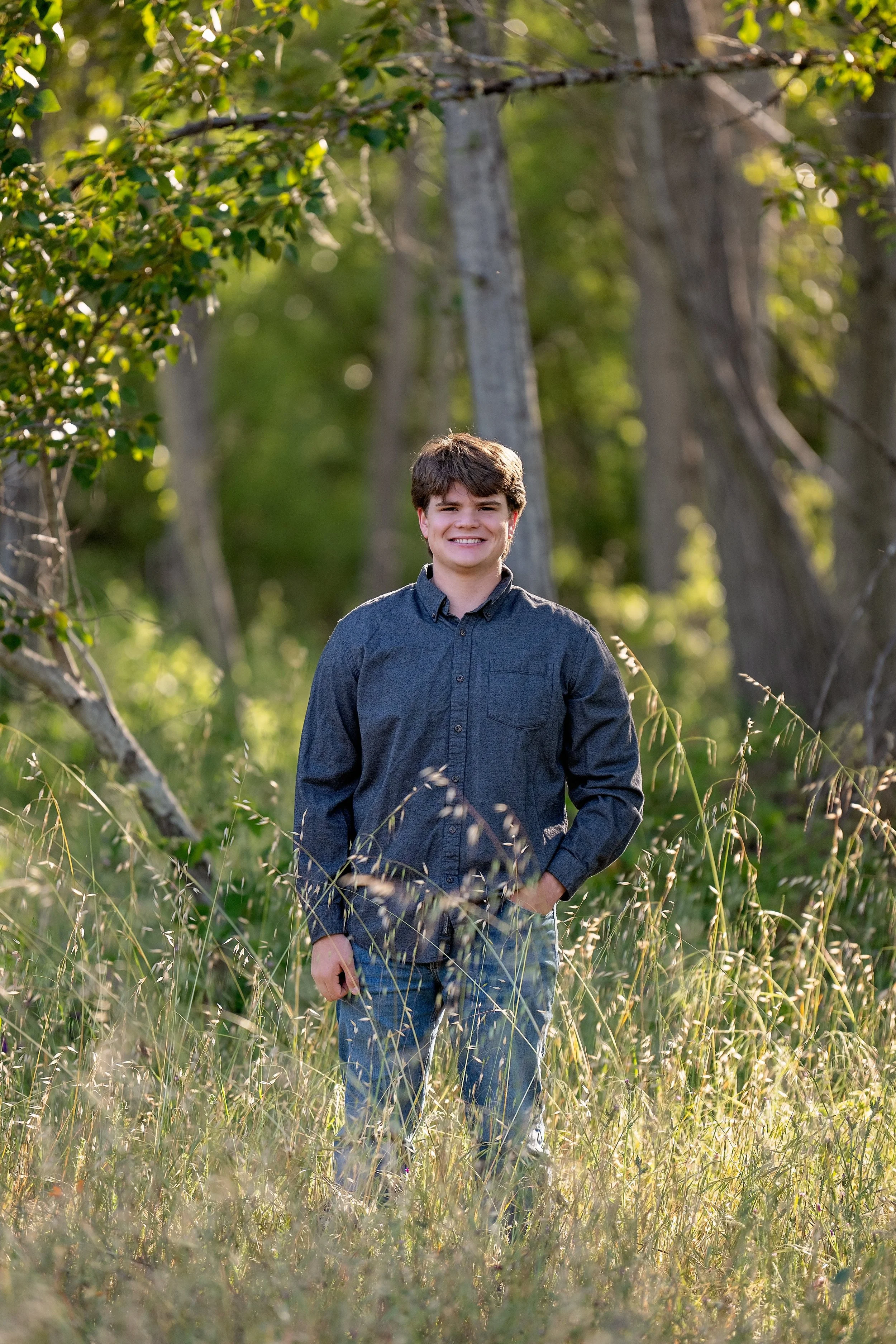 Senior portrait of Gianni surrounded by trees and tall grass at Garland Ranch in Carmel Valley, California.