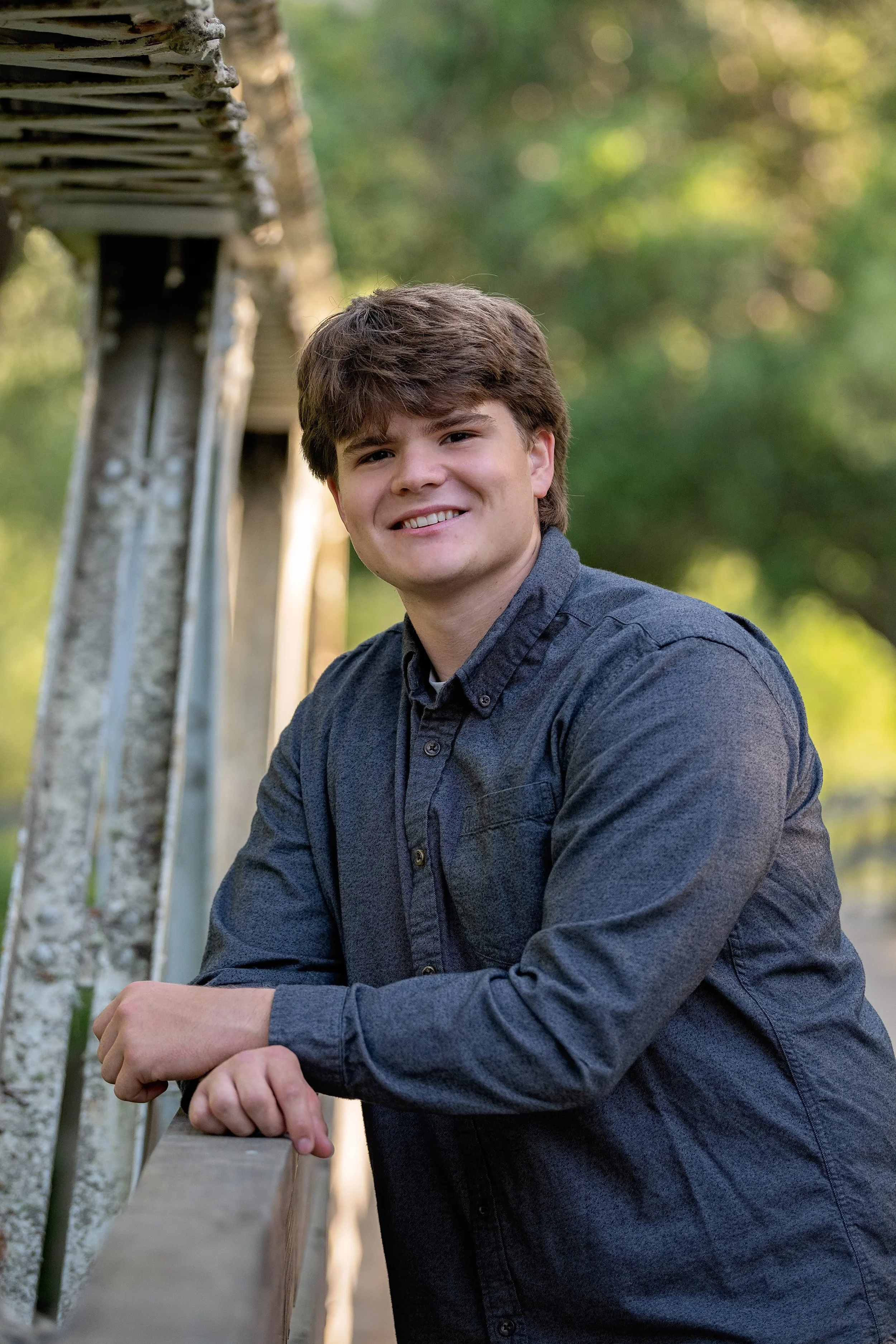 Close-up senior portrait of Gianni on the Garland Ranch bridge surrounded by soft green foliage.