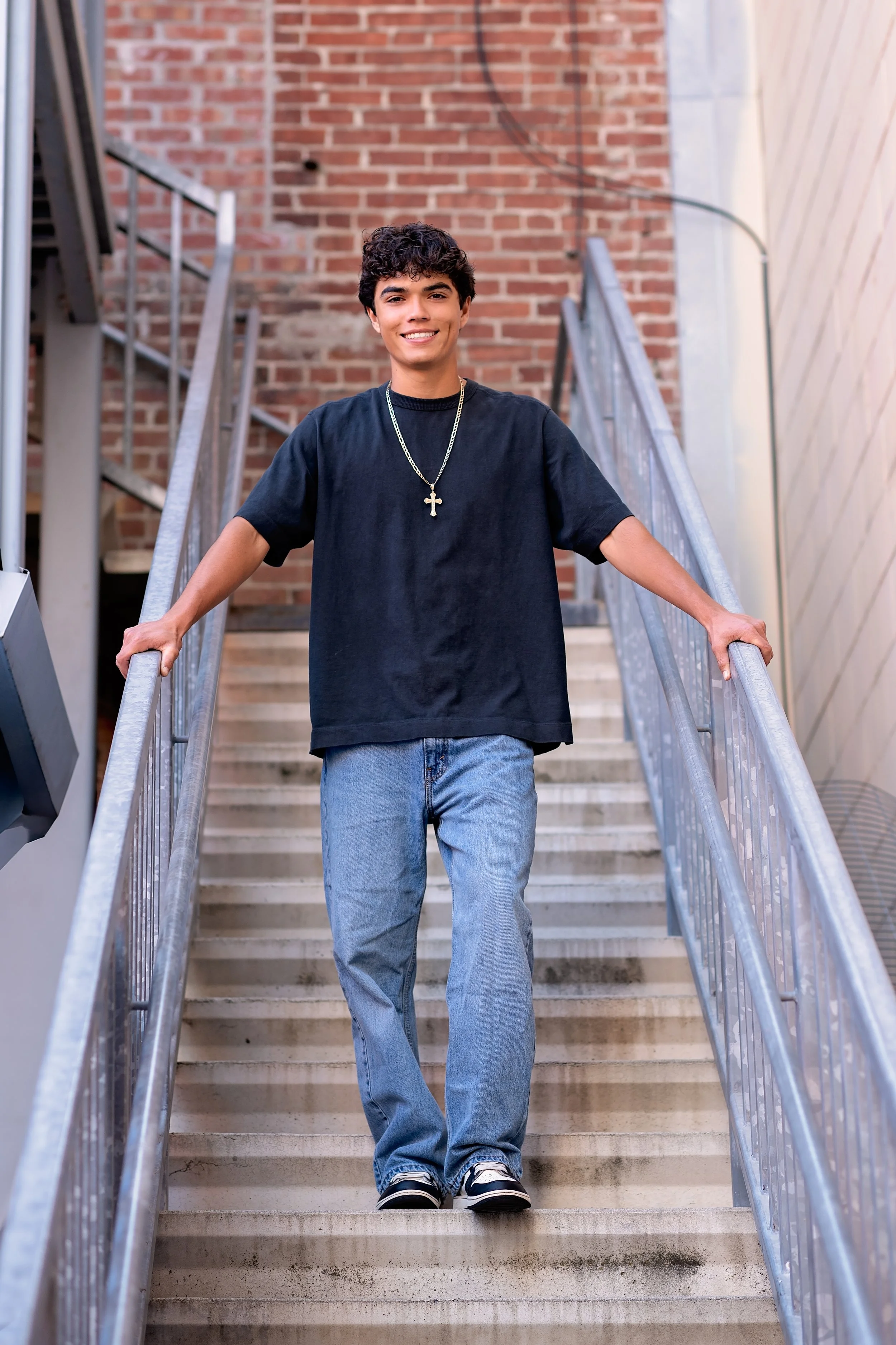 Salinas High School graduate Cruz posing on an outdoor staircase during his Downtown Salinas senior pictures.