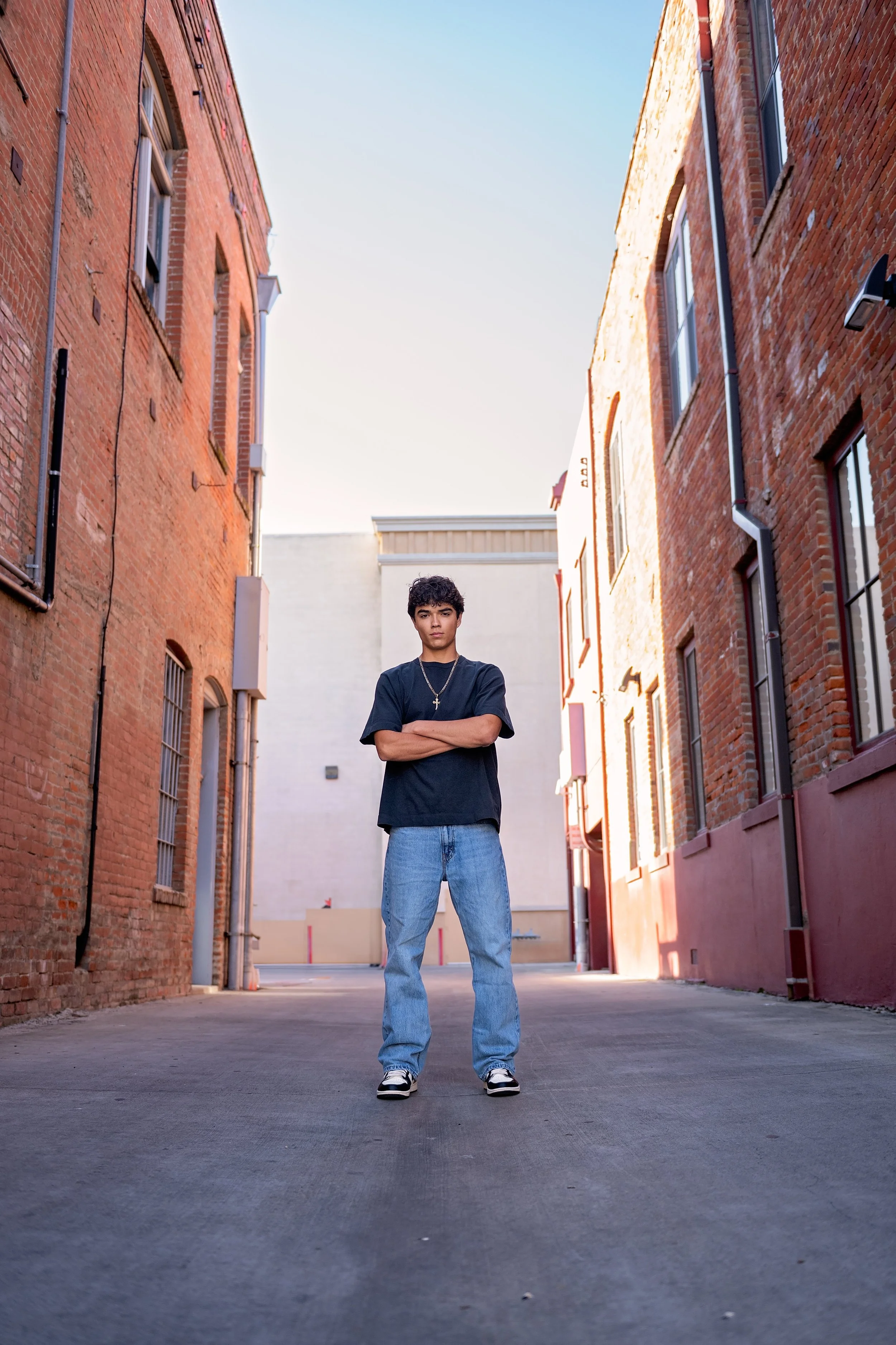 Salinas High School graduate Cruz standing between historic brick buildings during his Downtown Salinas senior pictures.