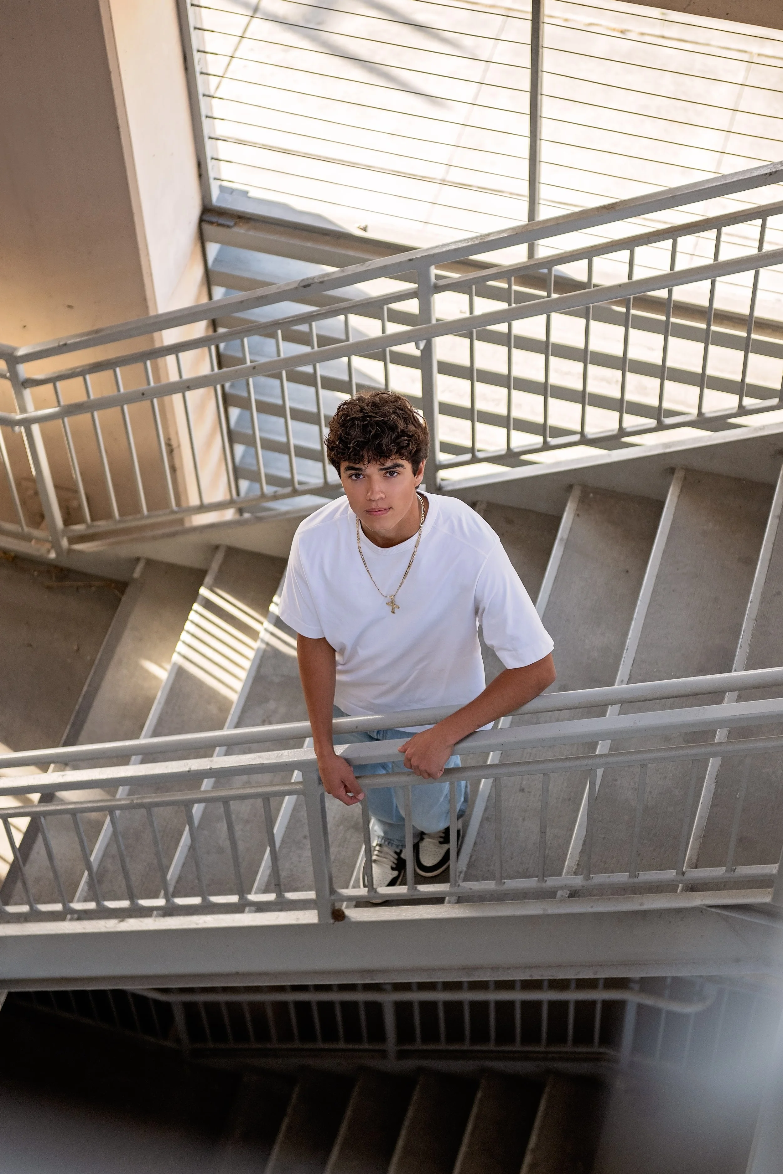 Cruz photographed from above on a modern staircase during his senior portrait session in Downtown Salinas.